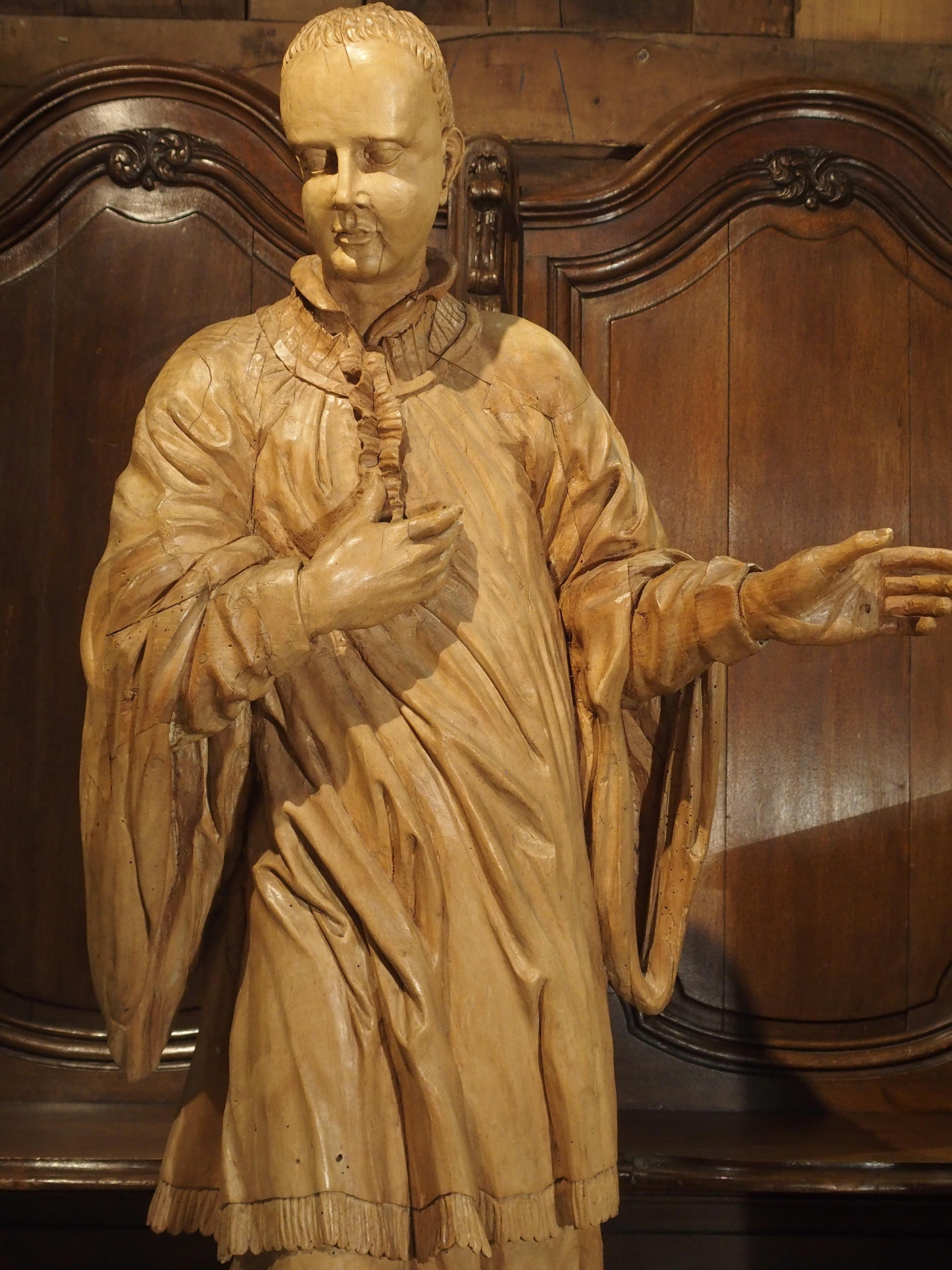 This beautifully hand carved, European limewood statue is of Saint Aloysius Gonzaga. The statue has incredible details, including his face, ears and in the many folds of his robe. The back is hollowed out and marked with black lettering of E S B and