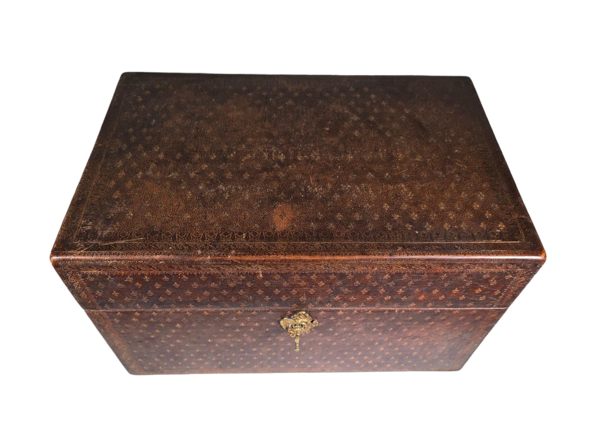 This exquisite liquor chest, accompanied by 18th-century glassware, epitomizes the opulence and sophistication of the era. Adorned with intricate leather embossing featuring floral motifs, accented with gilded iron detailing, this chest exudes