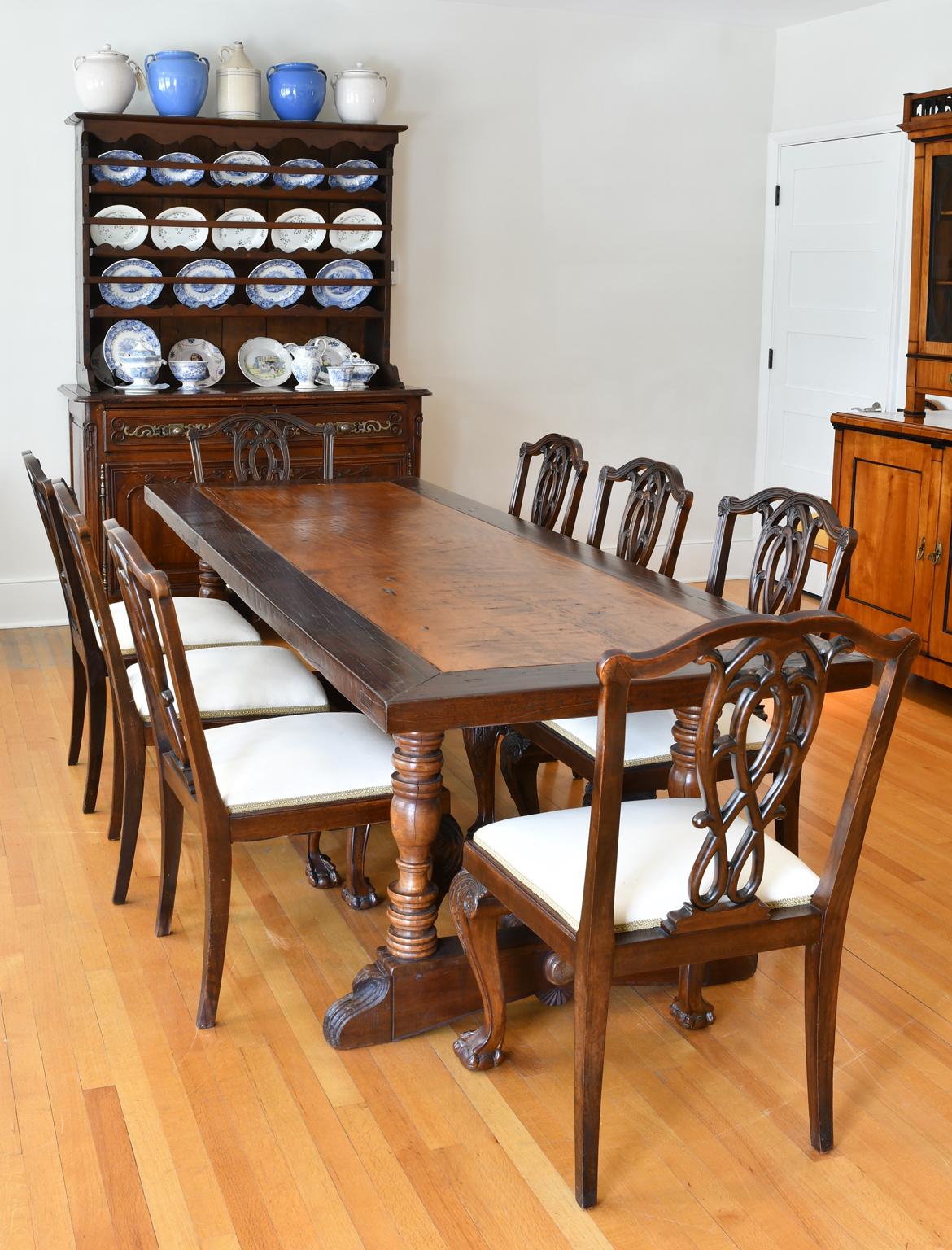 A gorgeous Spanish-colonial trestle-base dining table from the Philippines, made of various Asian hardwoods with 18th century carved and turned trestle base in a medium-walnut color with a contrasting caramel-colored molave-wood top that is banded