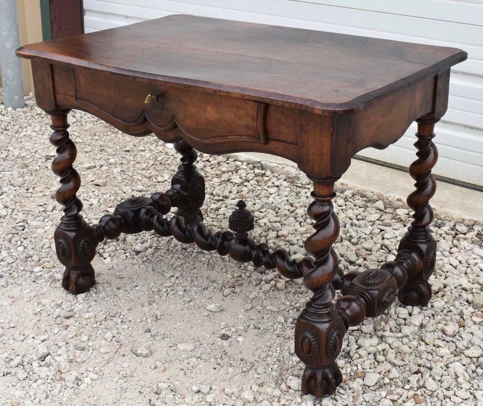An incredible 18th century solid walnut French center table, or desk. The table was built in the late 18th century in the Louis XIII style and using pegged construction. The table is decorated with a scalloped apron and barley twist legs sitting on