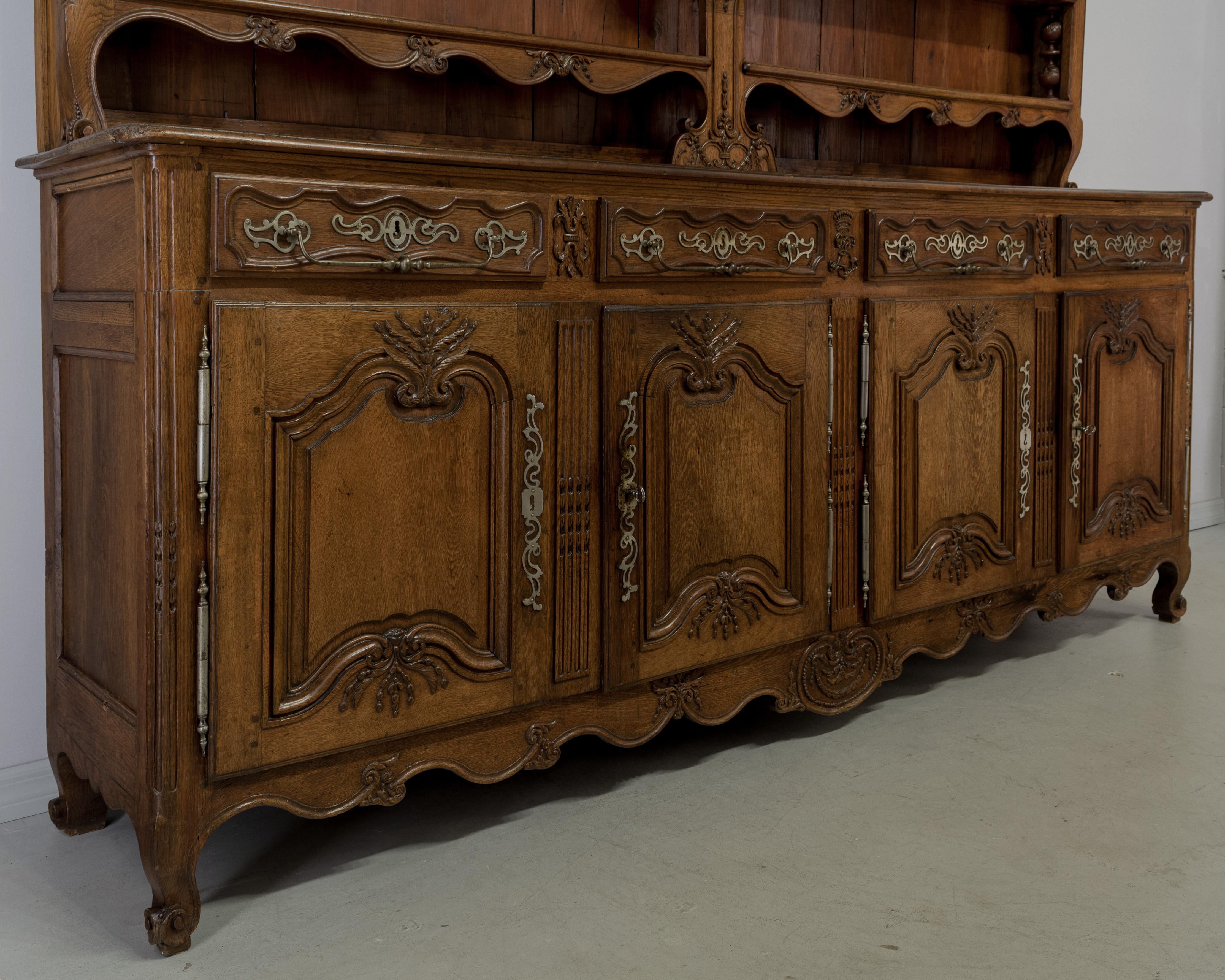 A grand 18th century Louis XV Country French buffet vaisellier from the Alsace Province made of solid oak. Exceptional quality with fine hand carvings throughout. Buffet has four dovetailed drawers with large pulls and four doors opening to one