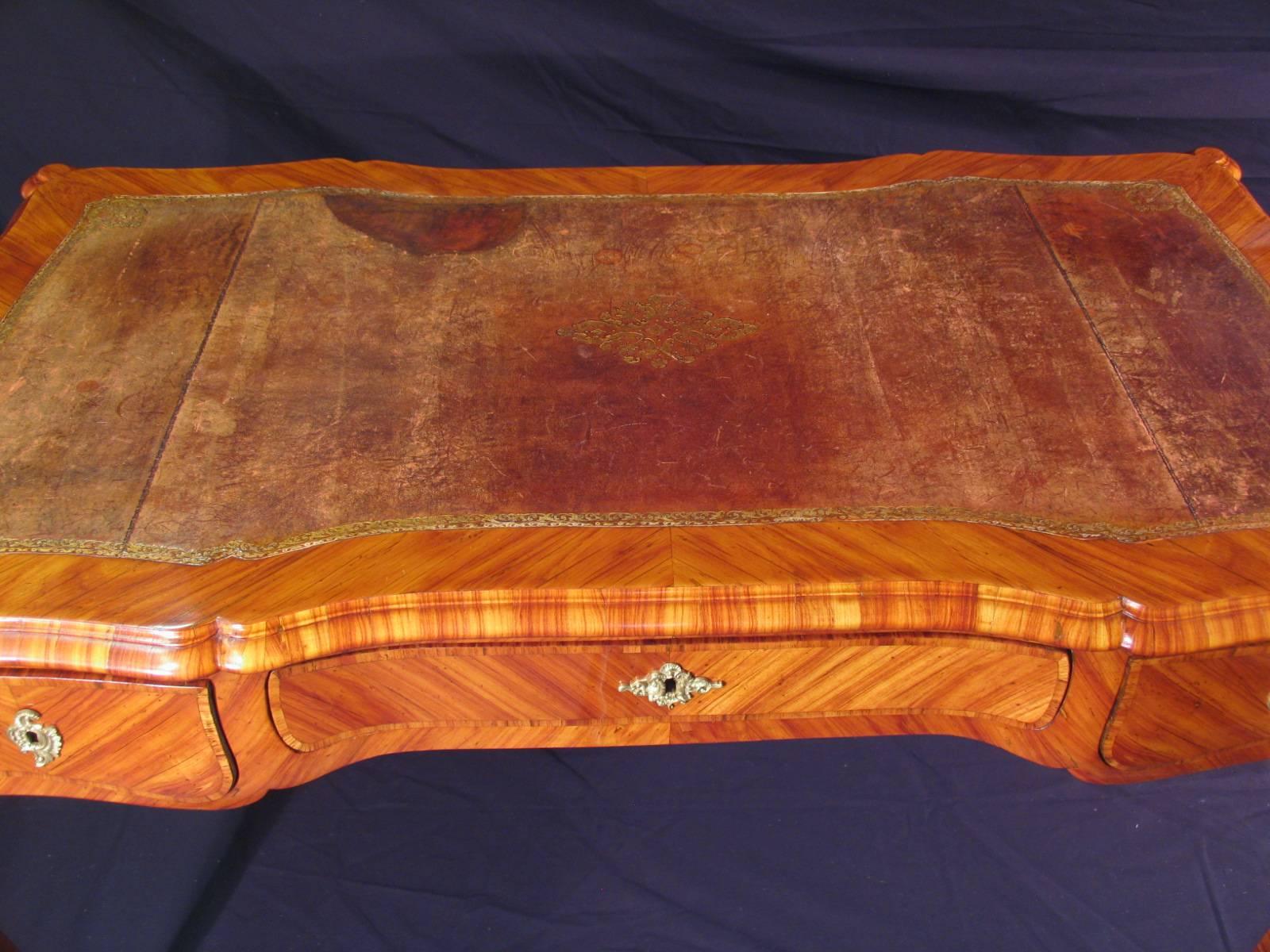 Bureau plat Louis XV, France, 18e-19e siècle. 
Le bureau plat est orné d'un beau placage de bois de rose et des ferrures d'origine en bronze. La surface d'écriture est doublée d'une surface en cuir doré. 
Le bureau plat est livré refini. Il est