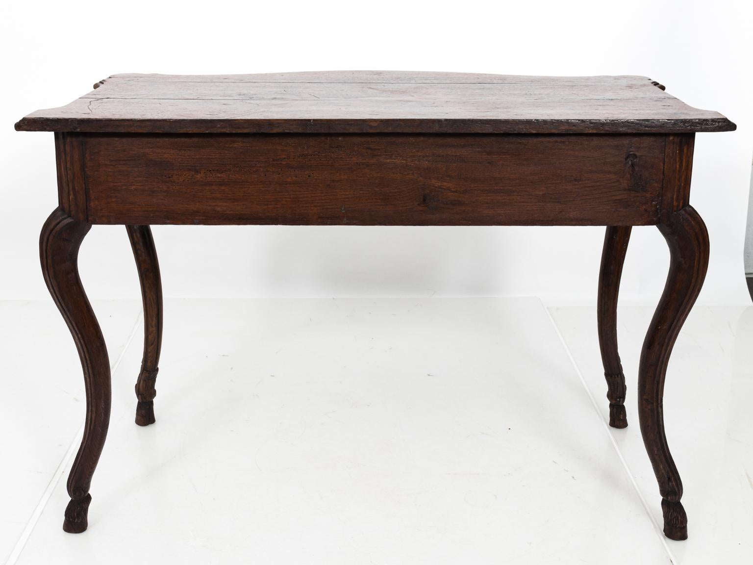 Louis XV oakwood console table with cabriole legs, carved hoof feet, and brass hardware, circa 18th century. Please note of wear consistent with age including a water stain and gaping in the wood on the tabletop.
