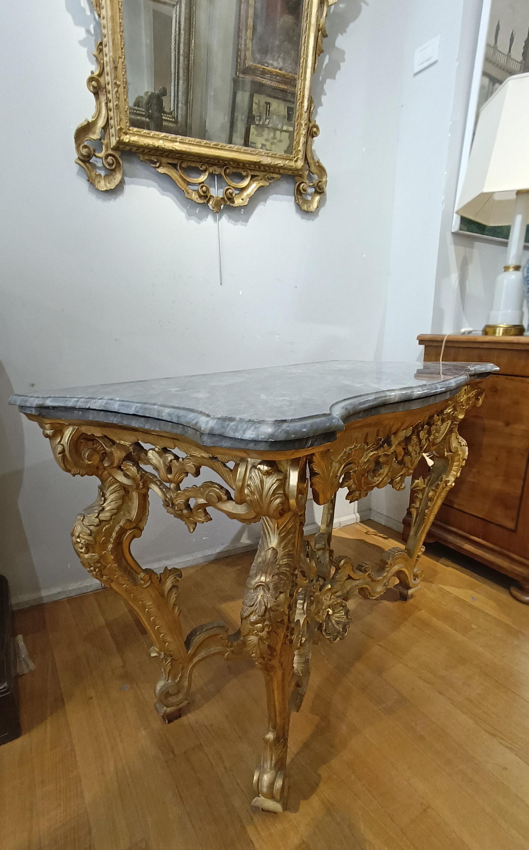 This mid-18th century Tuscan console table, belonging to the Louis XV period, is a piece of furniture of great elegance. Expertly crafted from fine pine wood, it was carved and gilded with extreme care, giving the piece a refined appearance. The