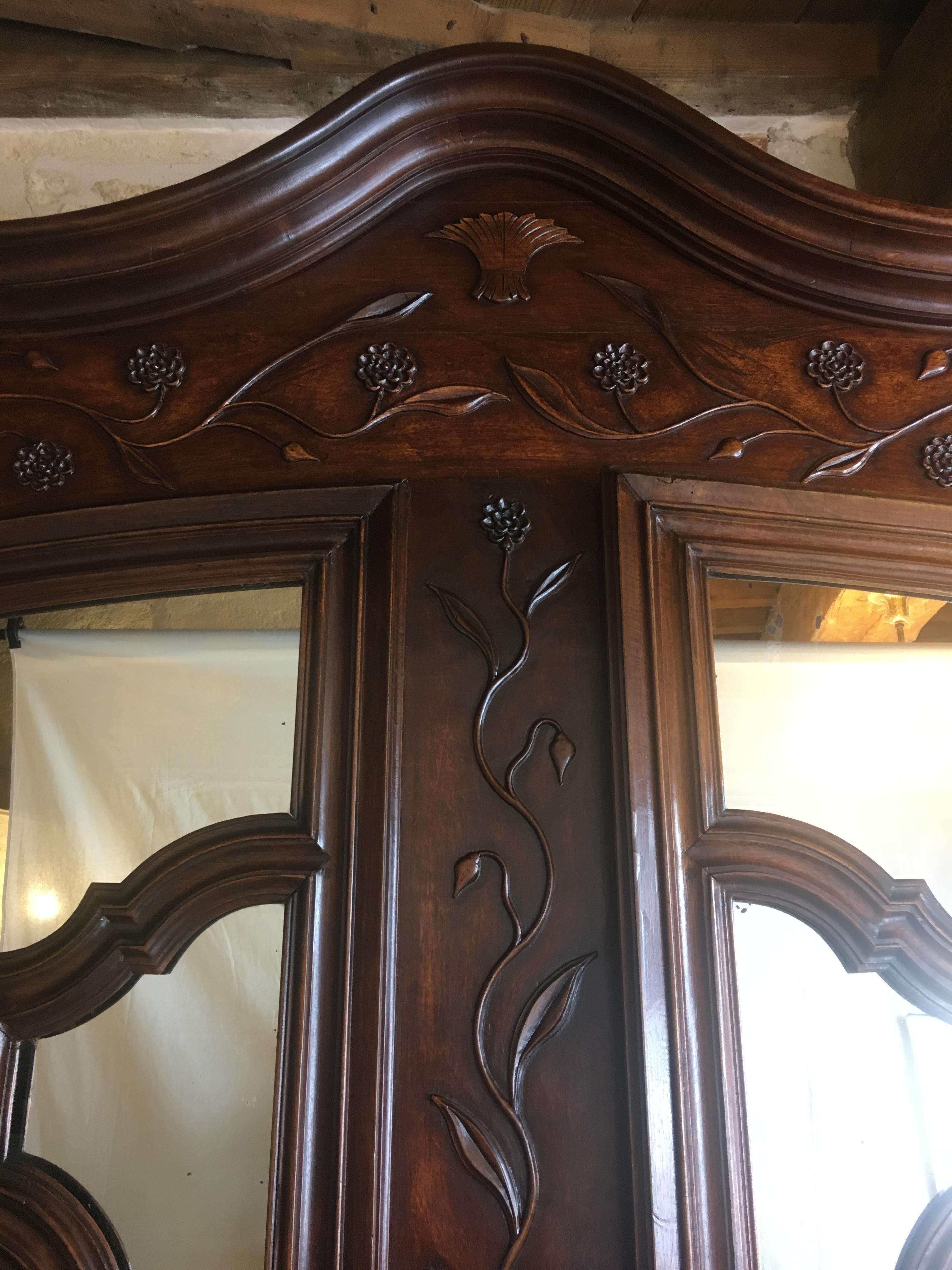 Rare and large 18th century French armoire or wardrobe constructed of walnut wood. This intricately carved Louis XV period piece features beautiful mirrored doors and a wonderful 