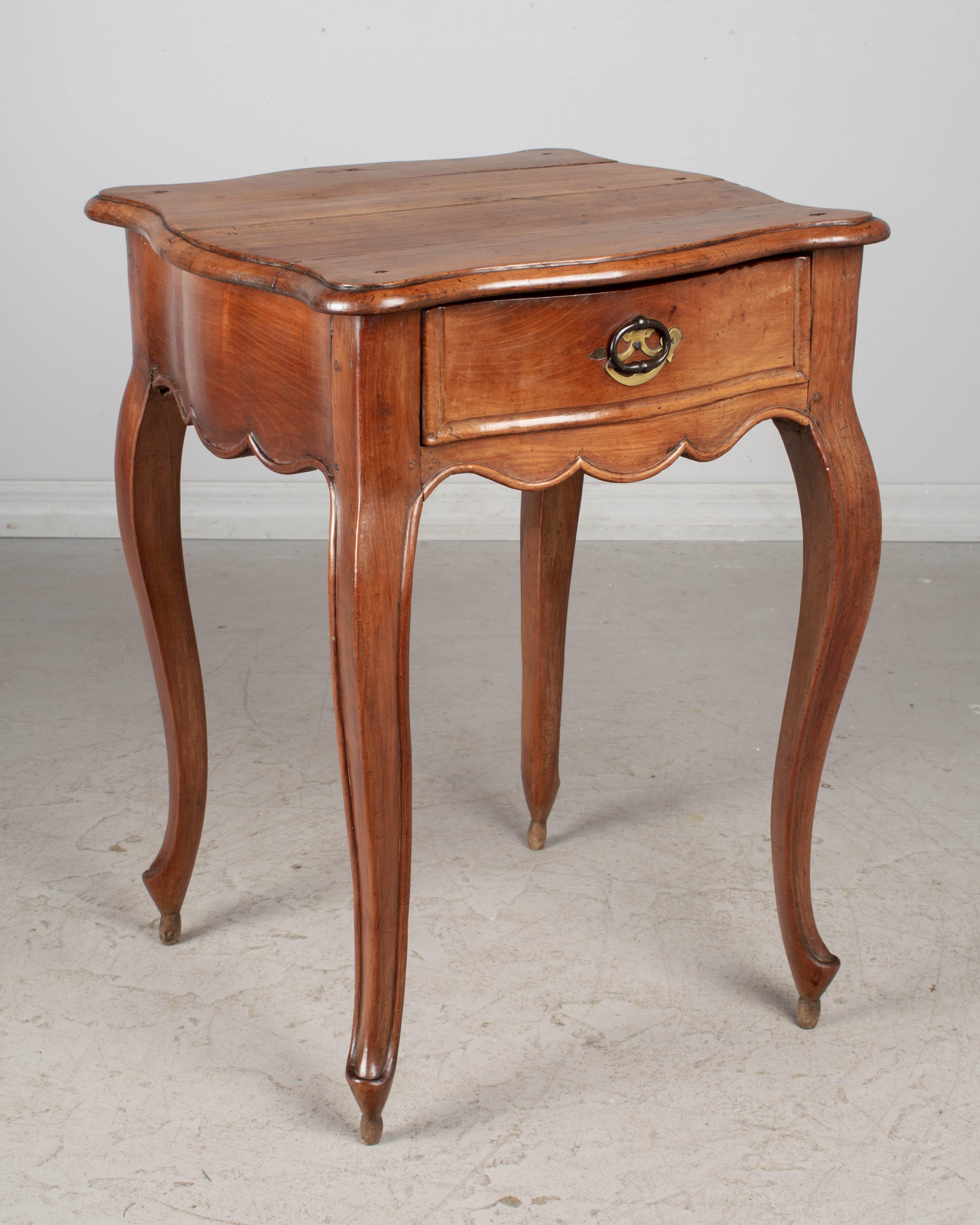 Französischer Beistelltisch Louis XV aus der Normandie, Ende des 18. Jahrhunderts, aus massiver Kirsche. Seltene, elegante Serpentinenform mit geformter Platte, dicker Schürze und Cabriole-Beinen. Schwalbenschwanzförmige Schublade mit eisernem