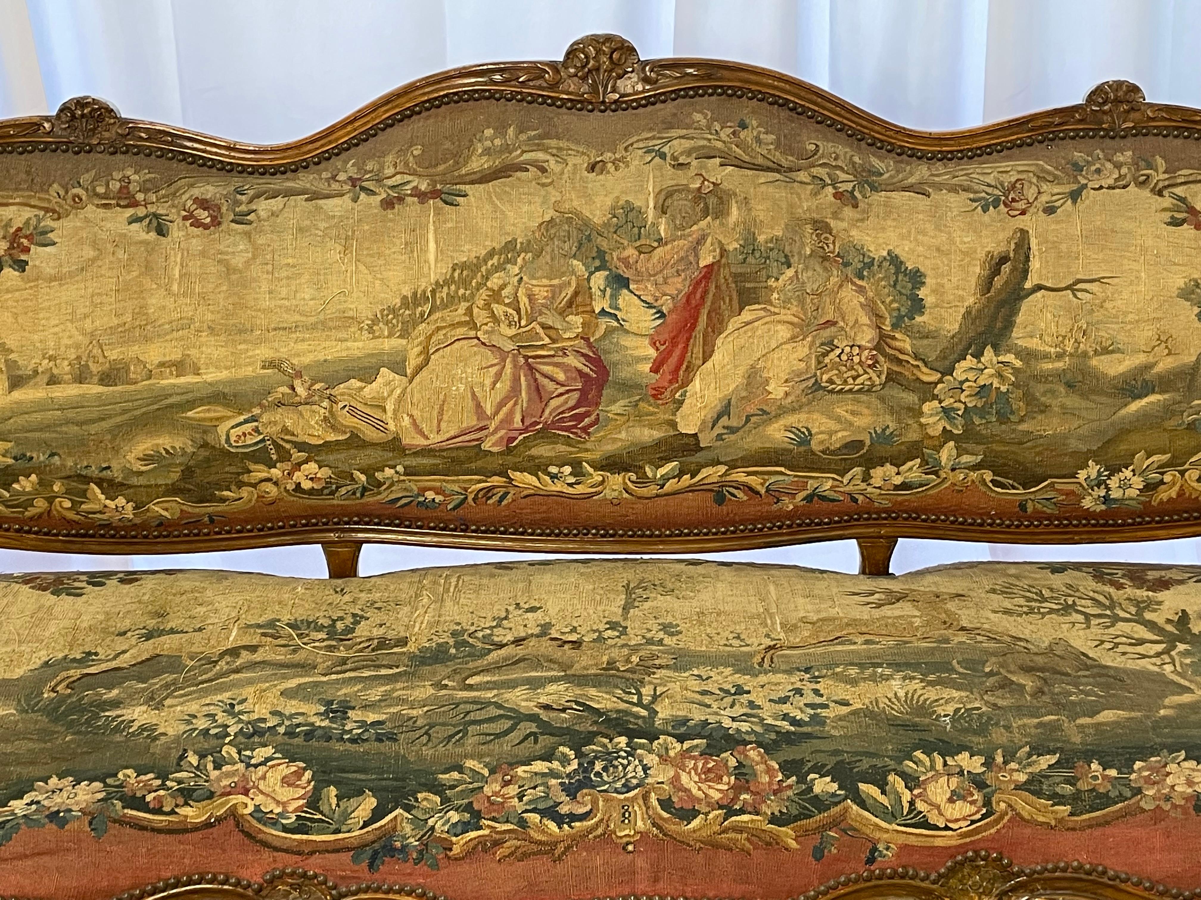 Louis XV fruitwood settee, late 18th century, the domed and padded back surmounted by a floral crest, joined by padded scrolling arms to the shaped seat, raised on molded cabriole legs headed by floral carving and ending in scrolled toes,