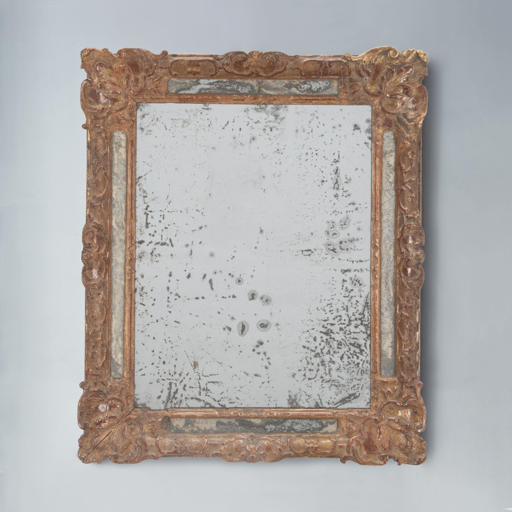 Precioso espejo Luis XV de madera dorada del siglo XVIII. 

La placa rectangular de mercurio está dentro de un marco moldeado con otros bordes espejados, con broches foliados de madera dorada en los ángulos. Diversos desconchones y pérdidas menores