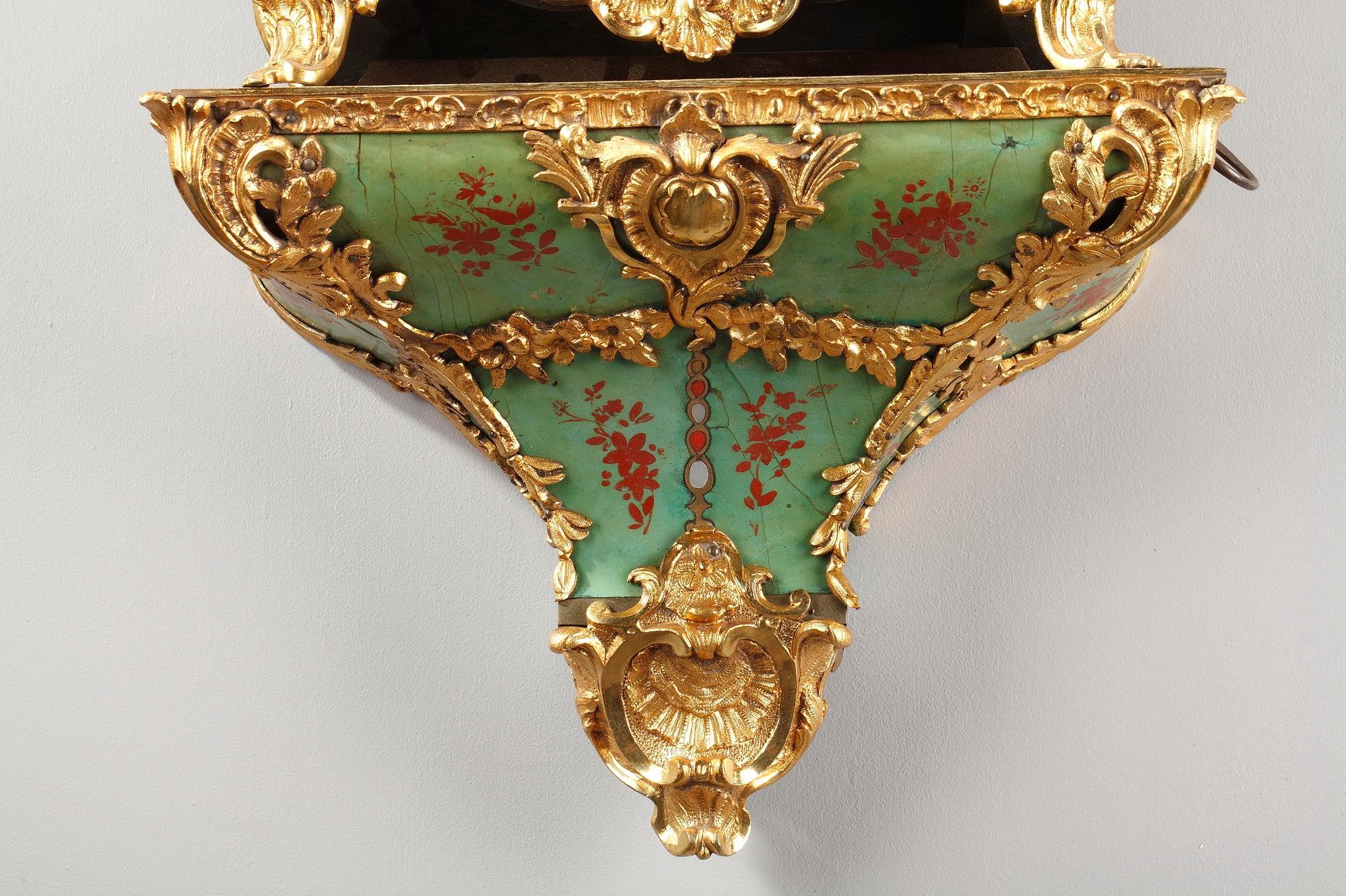 Louis XV cartel clock and wall console crafted of green horn and gilt bronze Rocaille decoration composed of foliated scrolls, flowers and vase. The horn is embellished with red bunches of flowers. The clock rests on four small arched feet decorated