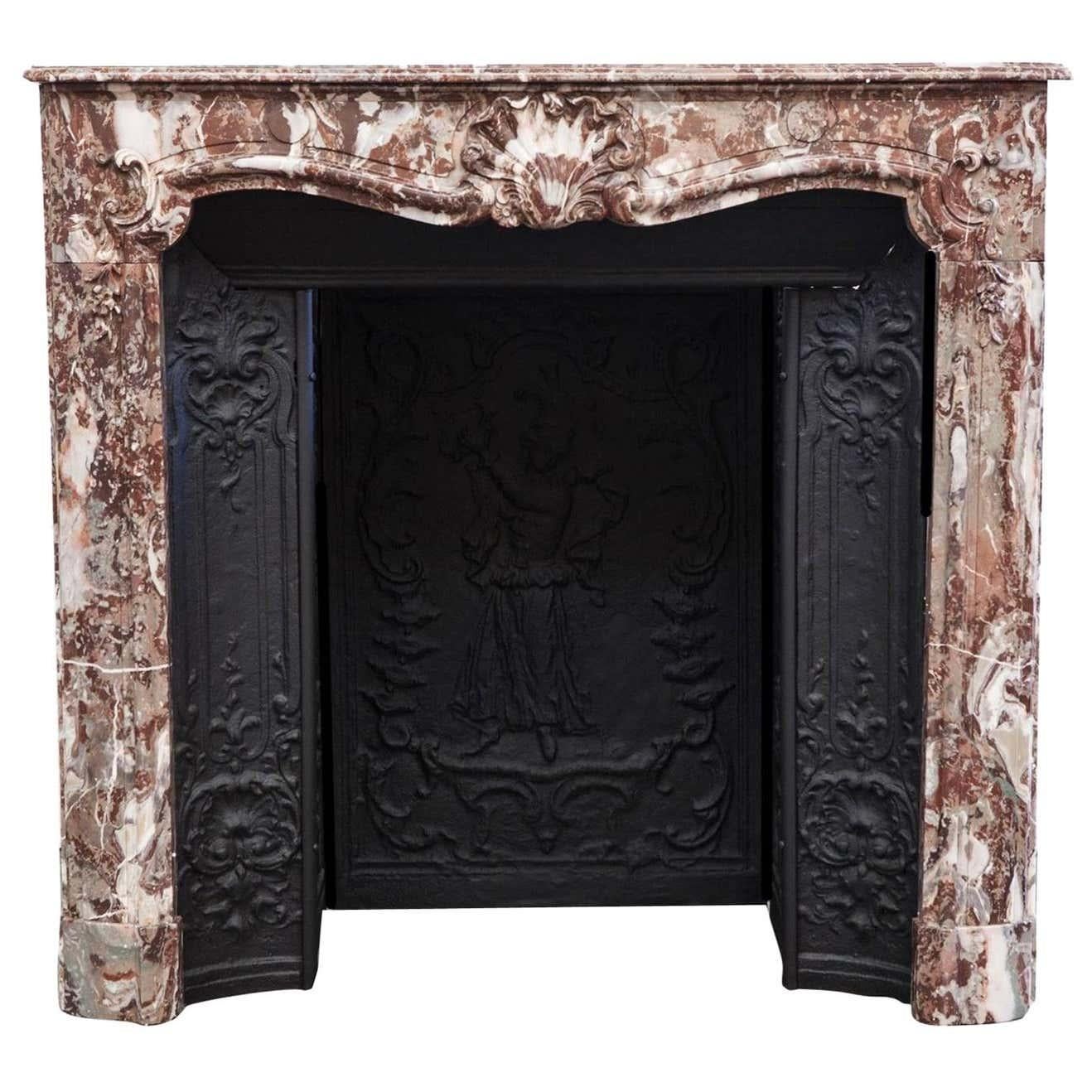 Beautiful late 18th century Louis XV Parisian rouge marble fireplace mantelpiece and cast-iron interior. This French fireplace mantel boasts a beautiful hand-carved shell centrepiece with detailed scrolls flagged along the frieze and jambs. The