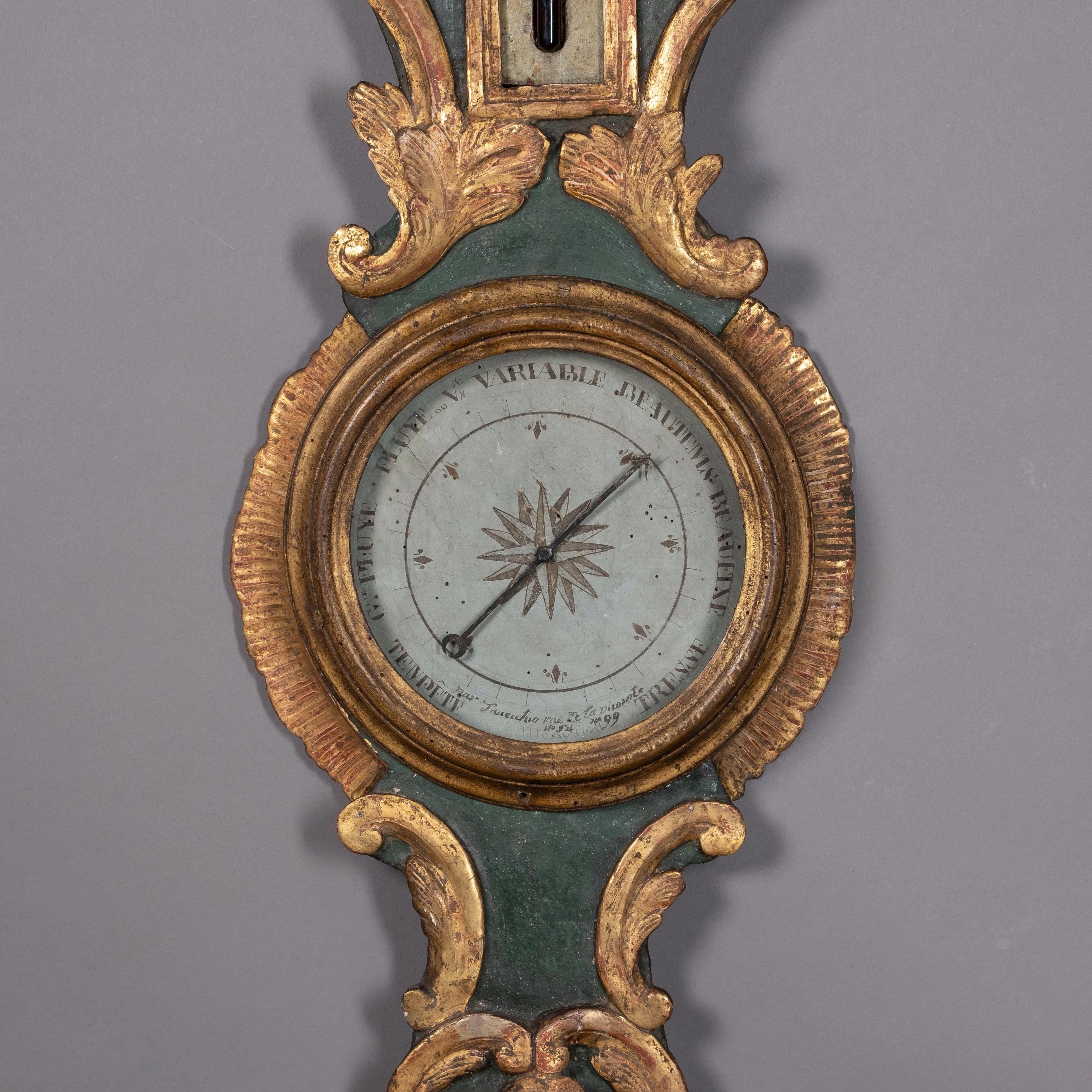 A Louis XV Period parcel gilded barometer of banjo form, the green painted body with carved giltwood rocaille work and C-scrolls throughout, housing a thermometer and weather dial.

The barometer no longer retains its rear mercury glass column and