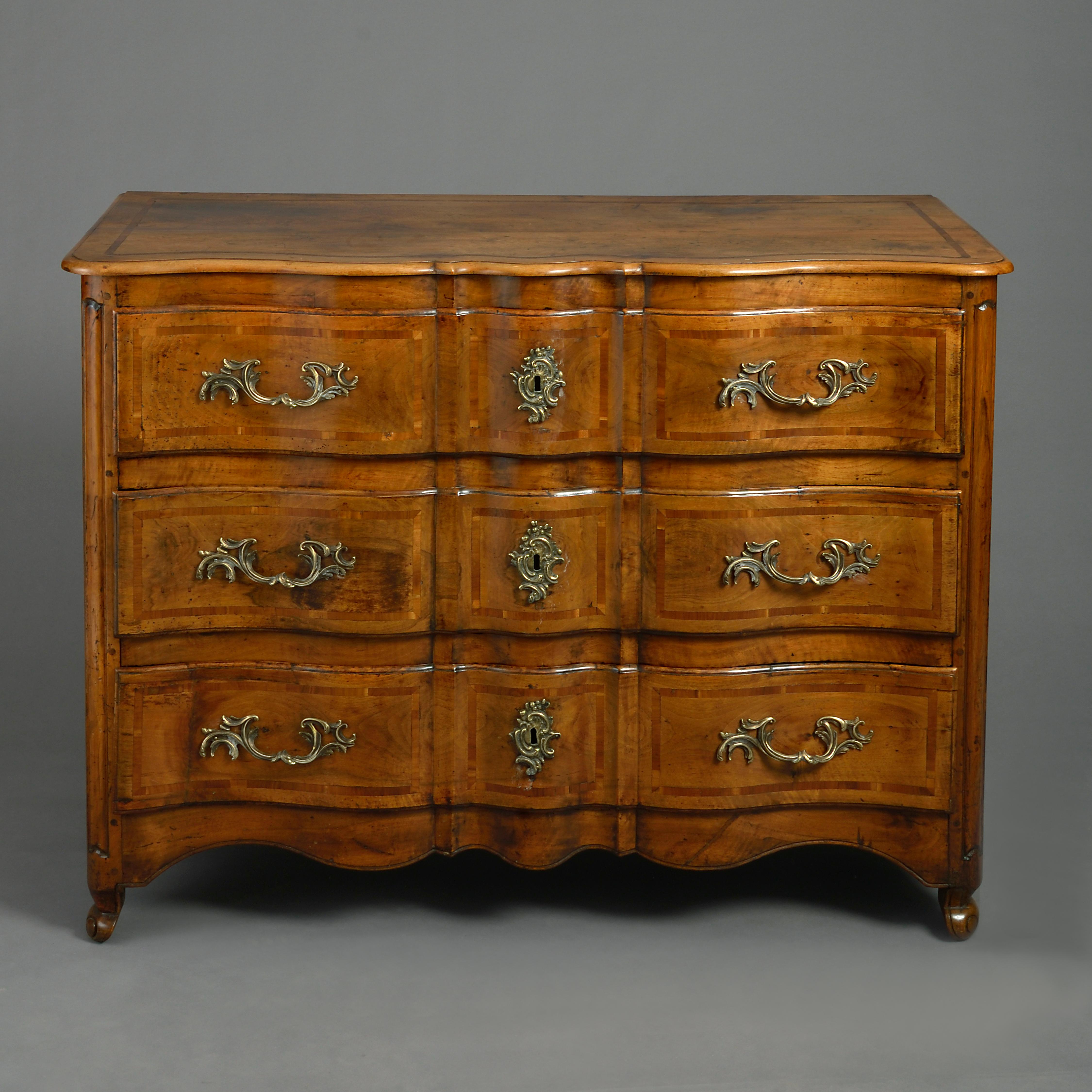 A mid-18th century Louis XV period walnut rococo commode with ripple front, the overhanging top above three inlaid drawers with scrolling brass handles, the sides with paneling, all raised upon cabriole legs.