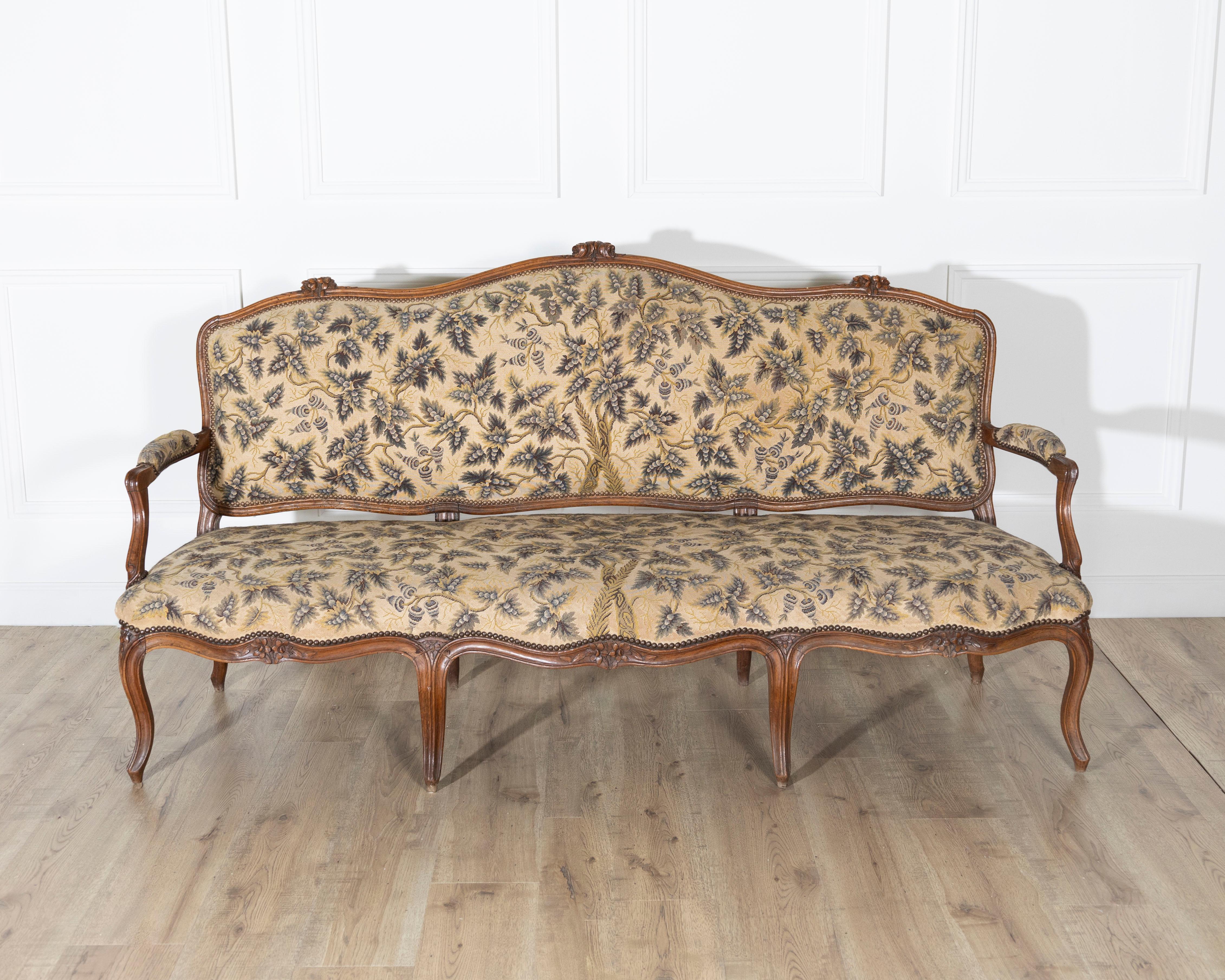 Ein elegantes Dreisitzer-Sofa aus dem Rhône-Tal im Stil Ludwigs XV. aus massivem Nussbaumholz mit anmutigen Proportionen und reichhaltigen handgeschnitzten Details. Die serpentinenförmige Rückenlehne und die geformte Sitzschiene sind mit zarten