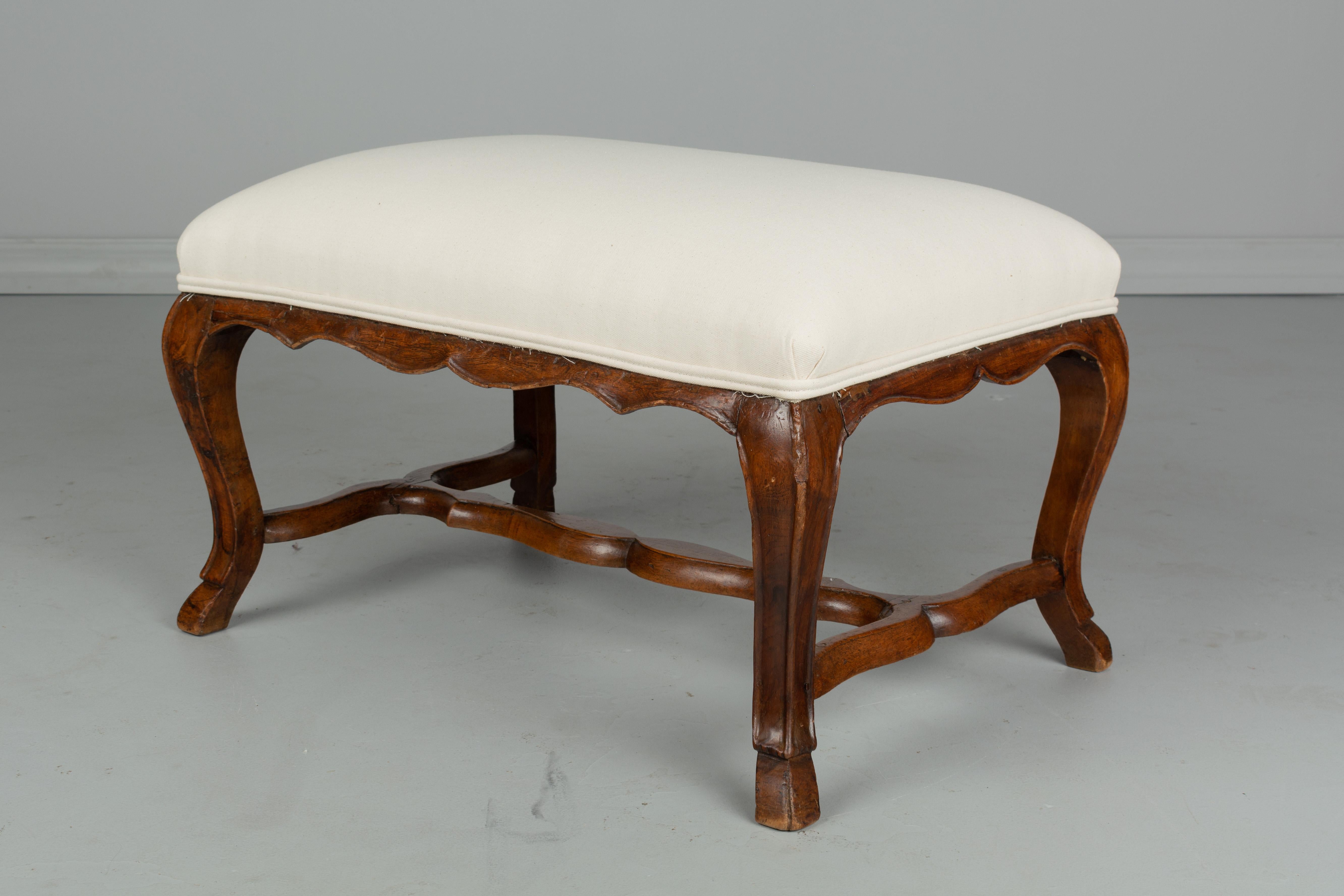 An 18th century French Louis XV style low foot stool made of solid walnut with elegant curved legs and stretcher. Newly reupholstered.
 