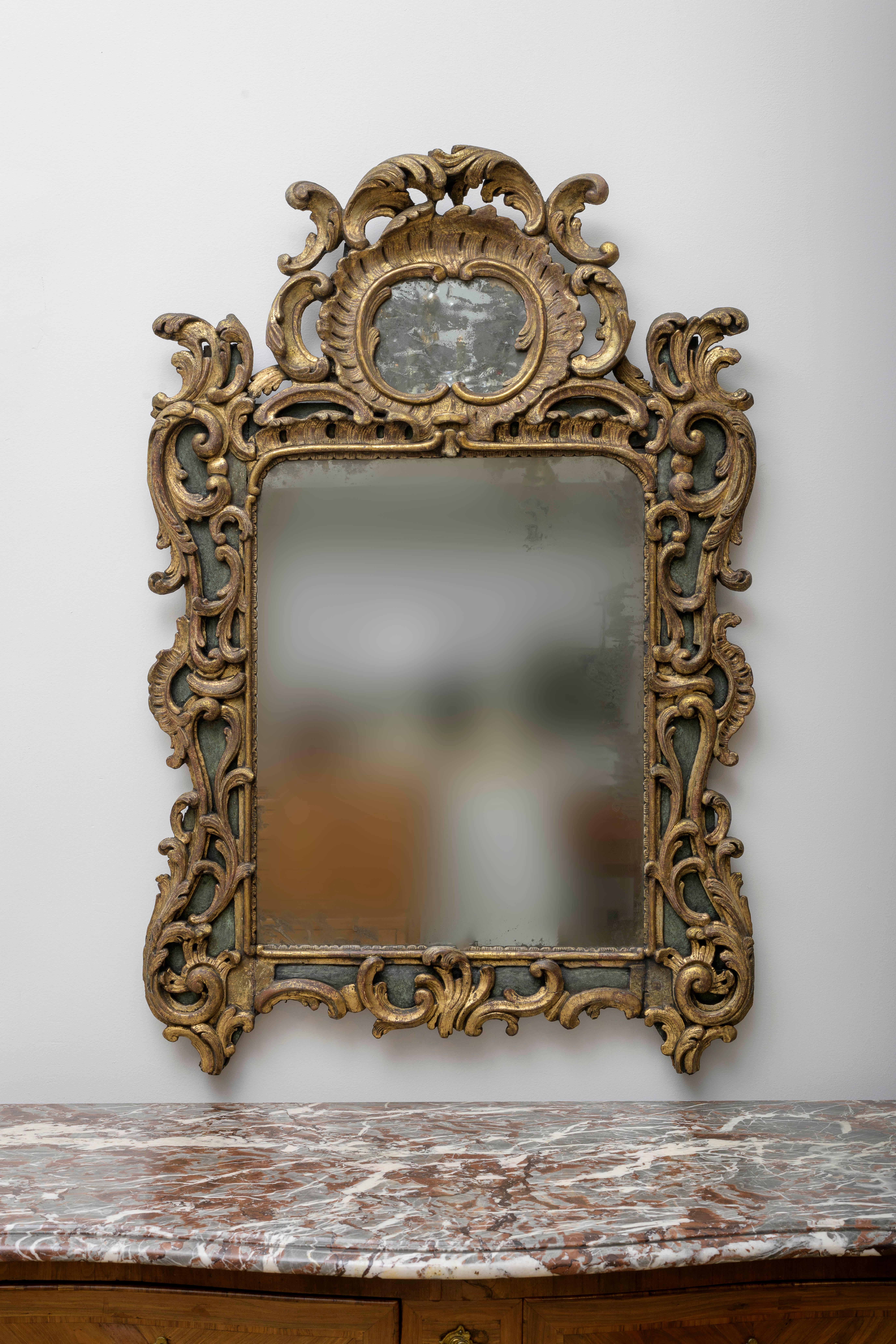 Beautiful richly carved and gilded mirror Beautiful proportions. 
This is a work of expertise as evident  by the quality of the abundant, deep and openwork and closed work frame. This is a typical Rocaille style,  from the early and middle 18th