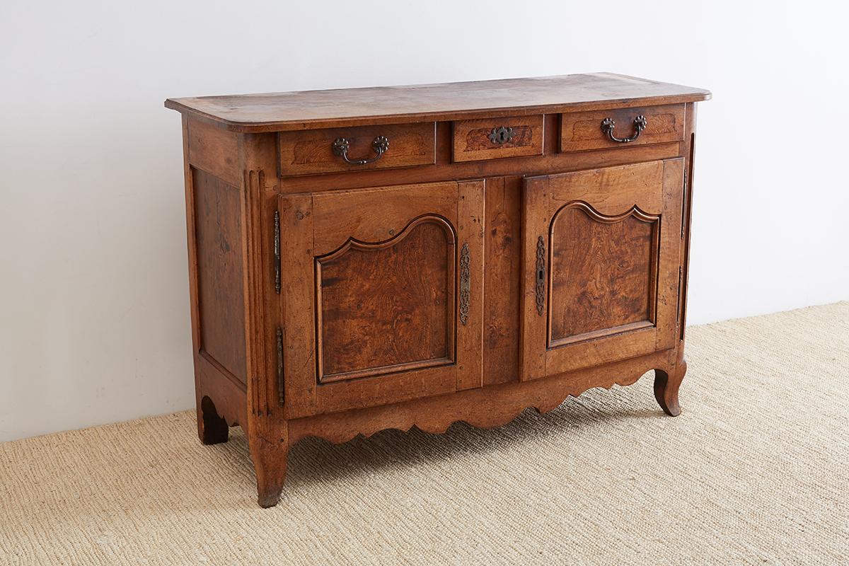 18th century French Louis XV period provincial walnut vaisselier or buffet side board. Features beautifully hand-carved panels with lovely wood grain patterns. The case has fluted corners with three drawers on top and two large storage doors below.