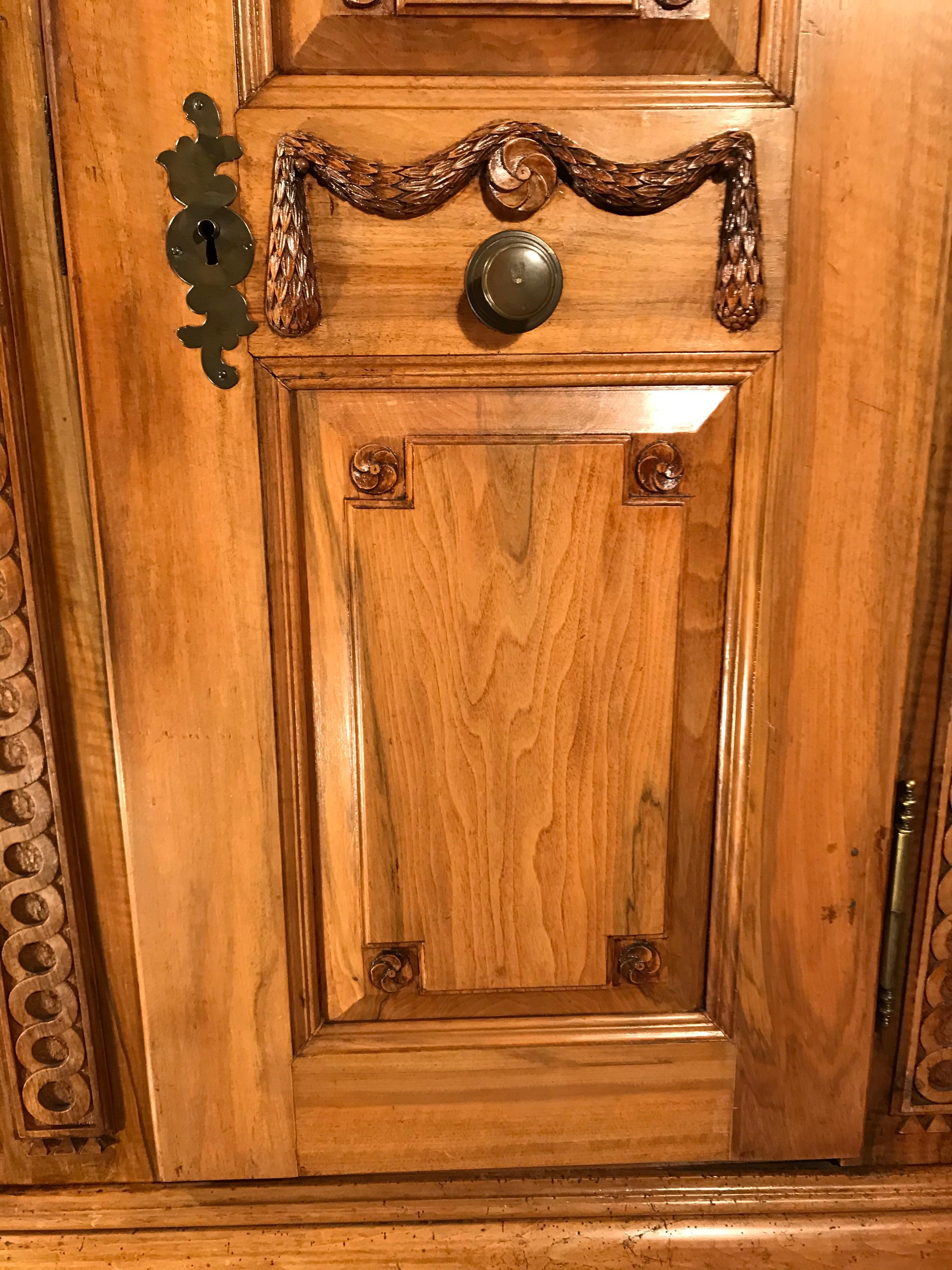 This original 18th century Louis XVI armoire, which was made in South Germany around 1780, stands out for its finely carved walnut details. Festoons and flowers decorate the two doors. Between the doors and on the sides are carved serpentine