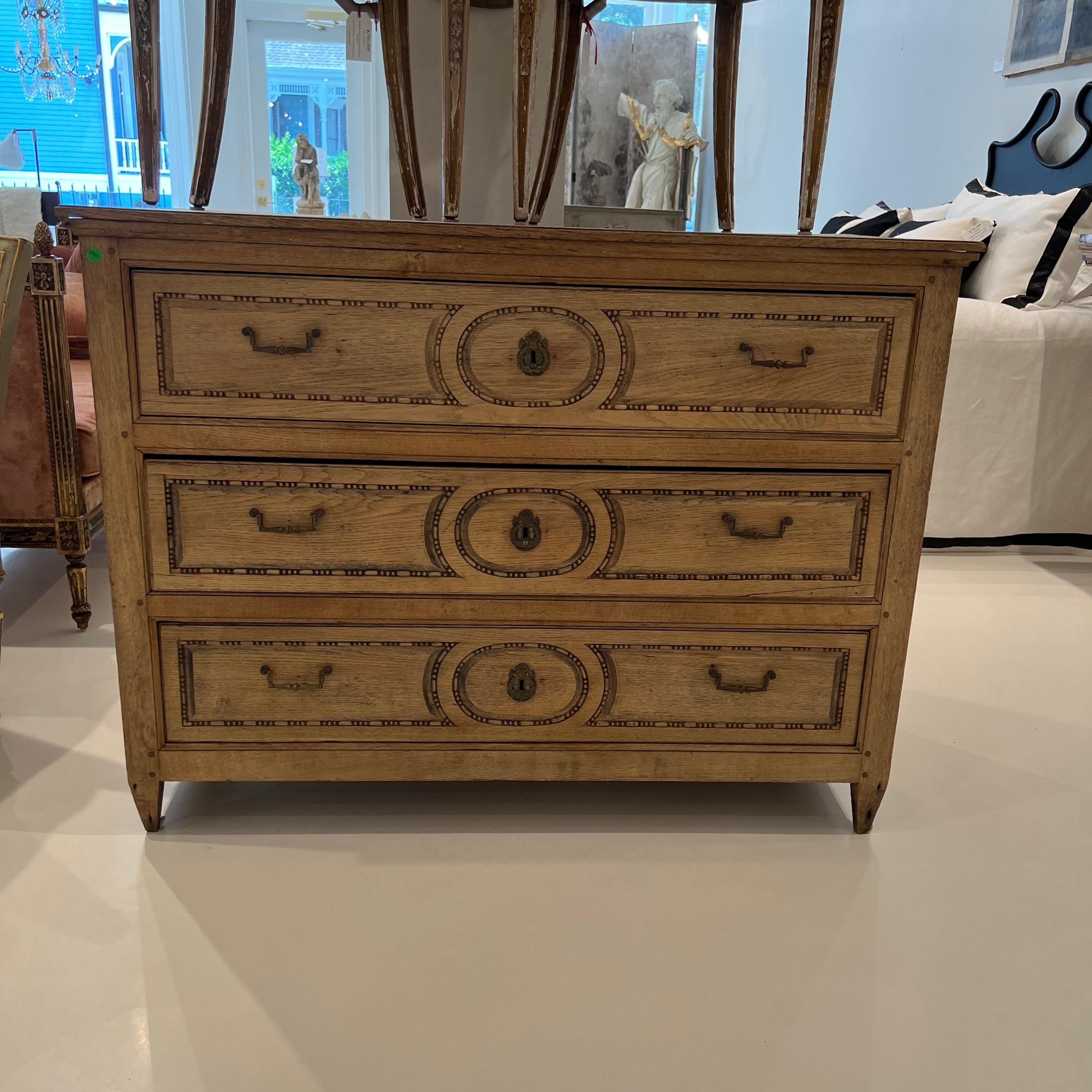 This fine chest is defined by softness and symmetry.  It has a pale oak finish and three ample drawers with fine detailed carving.  The sides are raised panels and the hardware is soft brass pulls in keeping with the overall mood, but then, bold