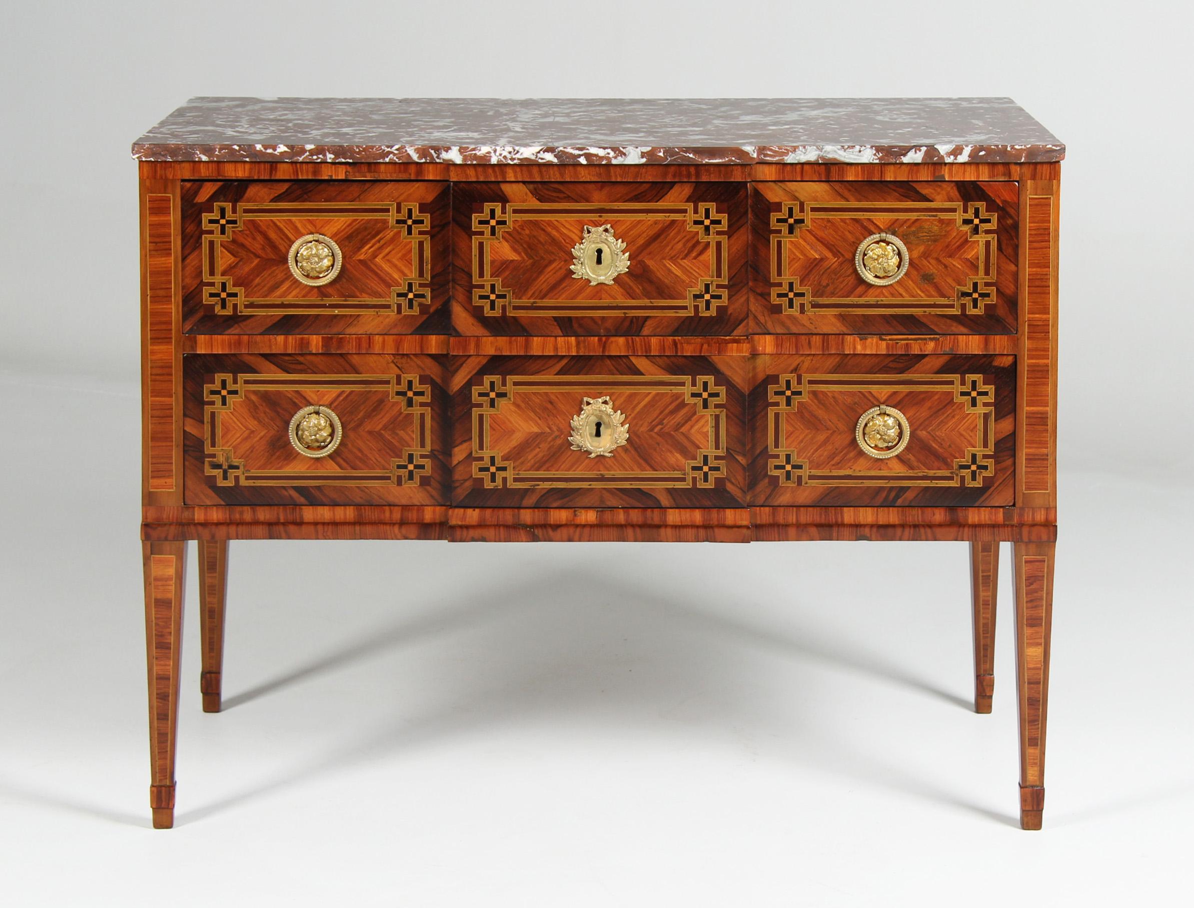 Louis XVI-Kommode aus dem späten 18. Jahrhundert mit feinen Intarsien und Ormolu-Beschlägen  

Abmessungen: H x B x T: 84 x 109 x 55 cm

Beschreibung:
Kommode mit zwei Schubladen auf hohen, spitz zulaufenden Beinen. Das Fehlen einer dritten