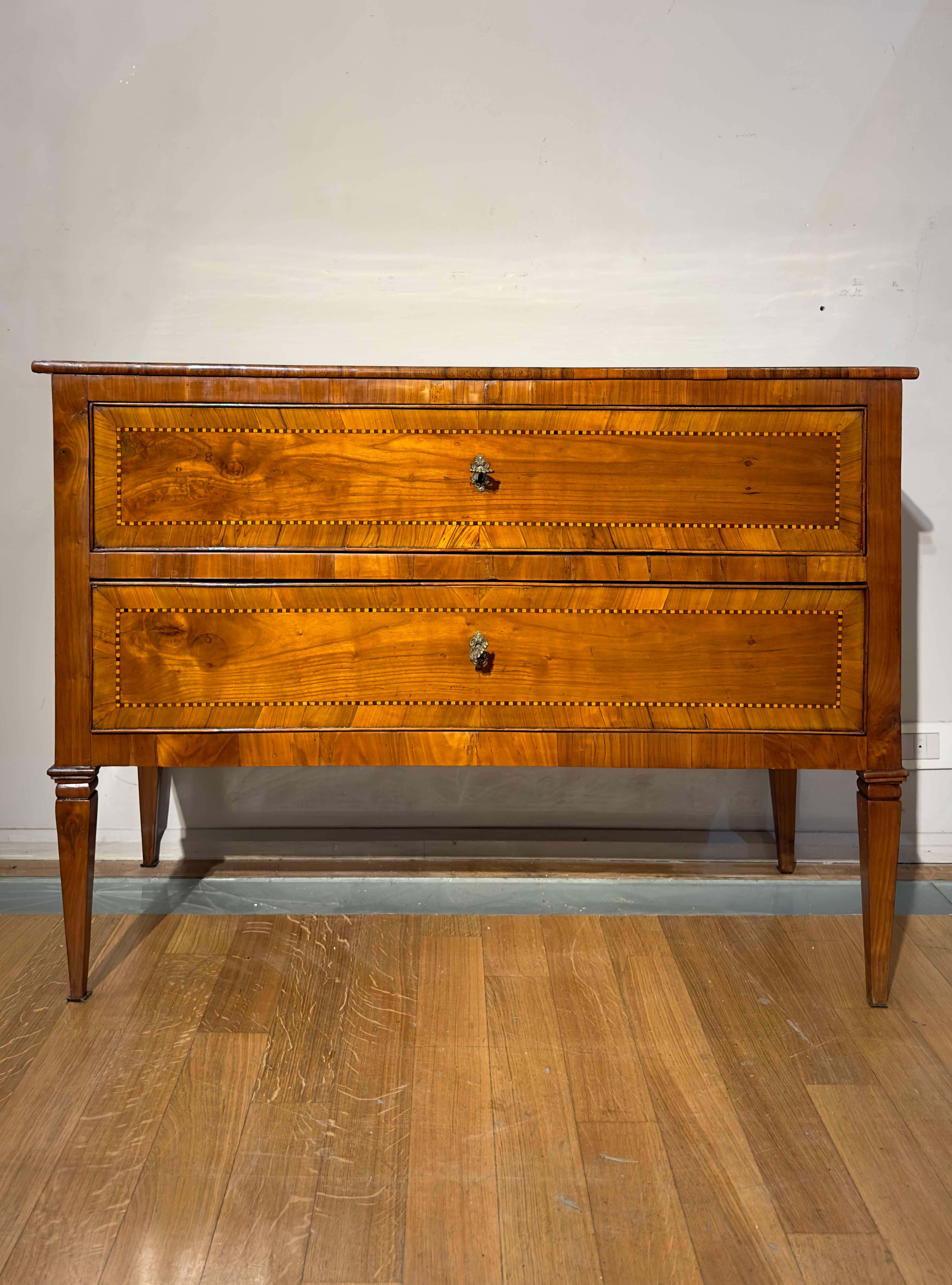 Neoclassical chest of drawers from the Louis XVI period, made of solid cherry wood with olive wood veneers. The elegant and refined design features a rectangular top supported by four truncated pyramid legs typical of the Louis XVI style. The piece