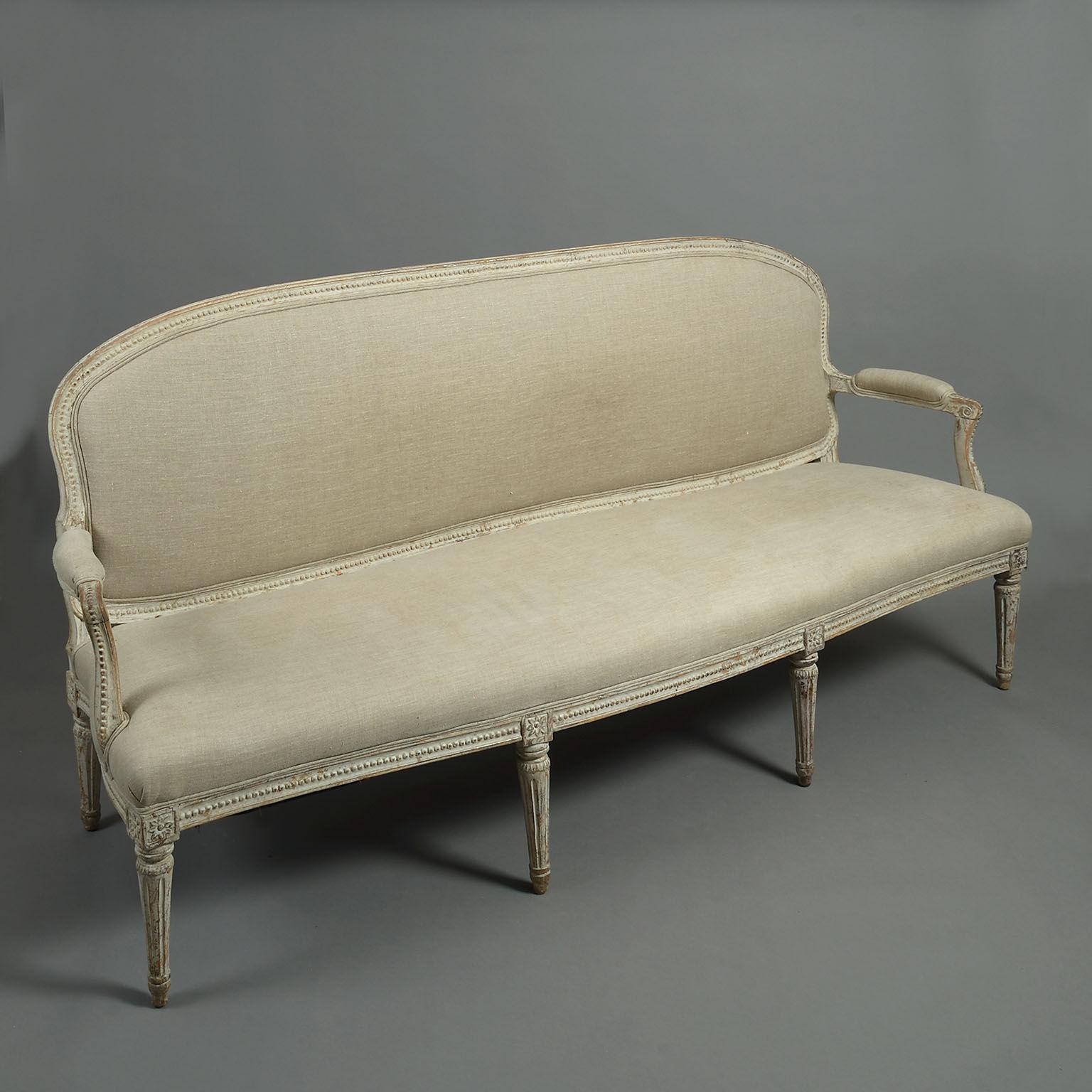 A Louis XVI sofa or canape with elegantly moulded frame carved with bead decoration surrounding the cartouche-shaped padded back. The out-swept padded arm with scrolled fronts supported on similarly bead-decorated arm supports. Upholstered in