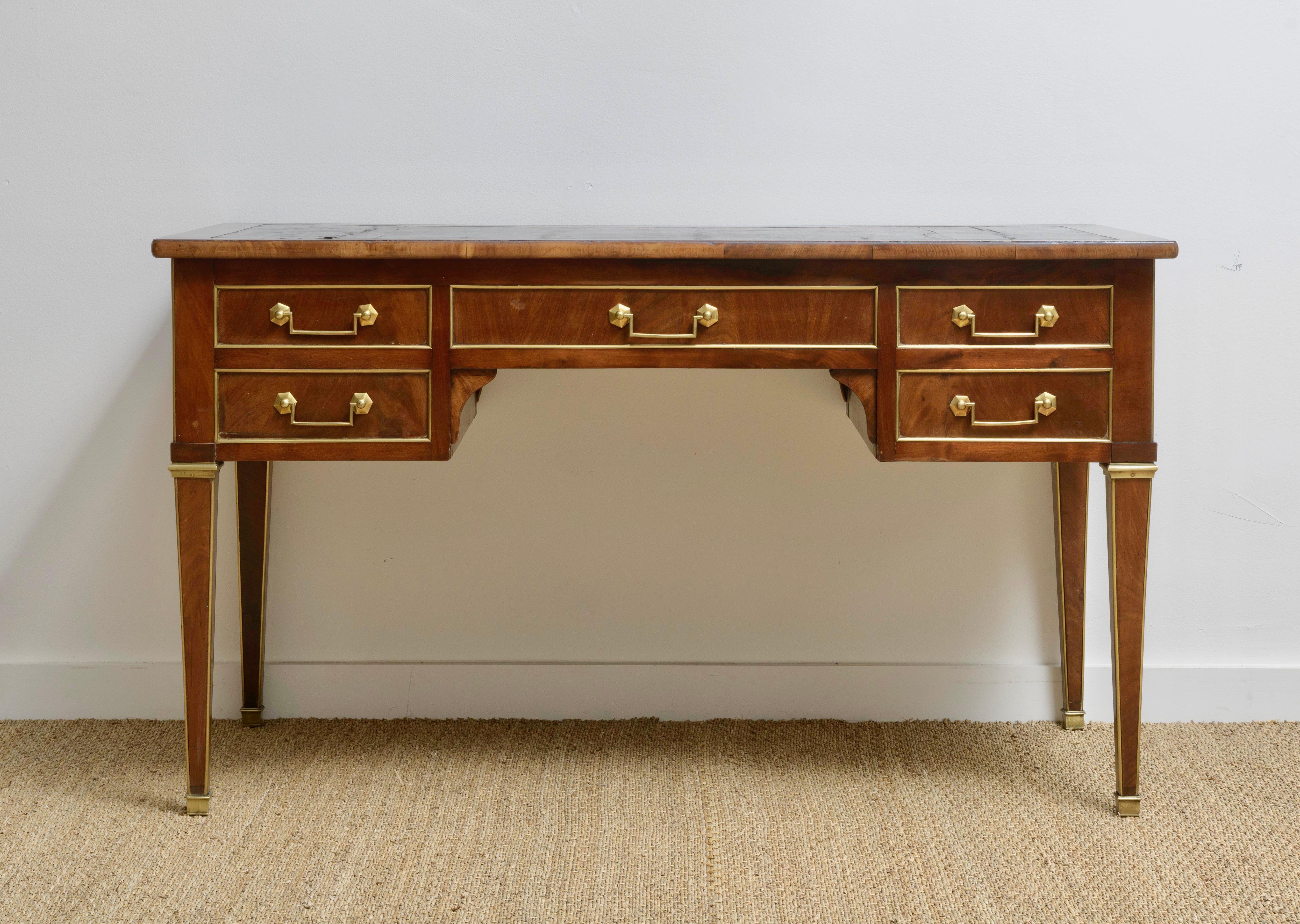 Beautifully scaled mahogany and mahogany veneer bureau plat from the Louis XVI period Double-sided decoration, with lateral pulls., resting on elegant tapered legs, with brass beading and feet (original) Decoration of fine brass fillets and a brass