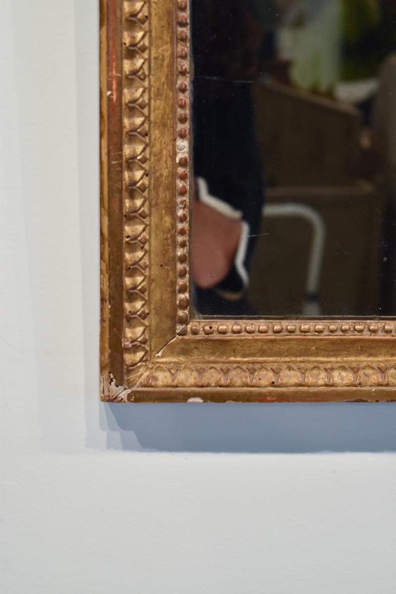 This exquisite Louis XVI mirror dates back to the 18th century, a time when French design was synonymous with elegance and sophistication. The mirror’s frame is meticulously carved from solid wood and adorned with a luxurious gilded finish,