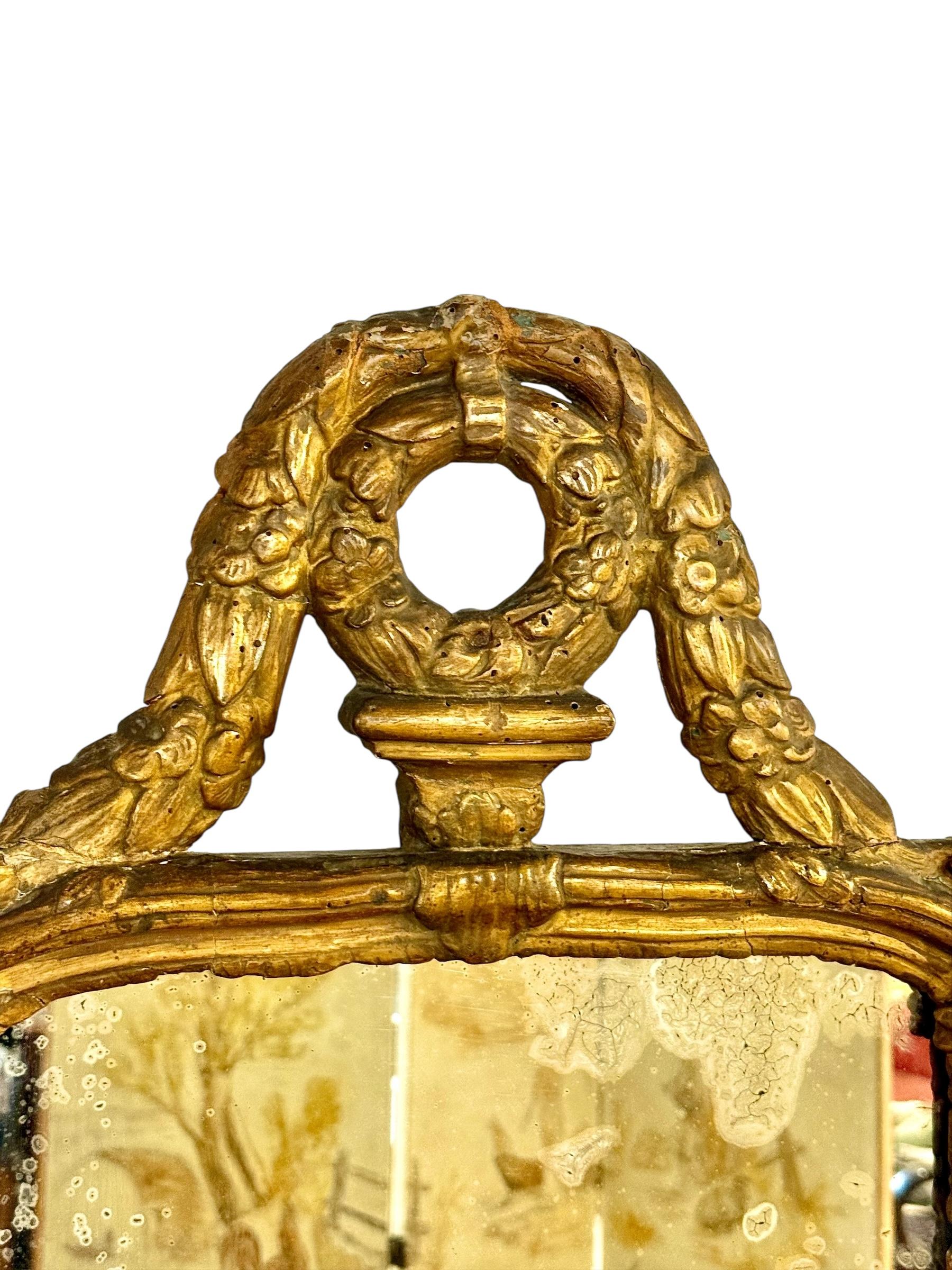 Elegante y auténtico espejo francés de madera dorada del siglo XVIII, de estilo Luis XVI, datado hacia 1780. Esta pieza está elaborada en madera de haya tallada con su dorado original en paquetería, ricamente detallada con motivos clásicos como