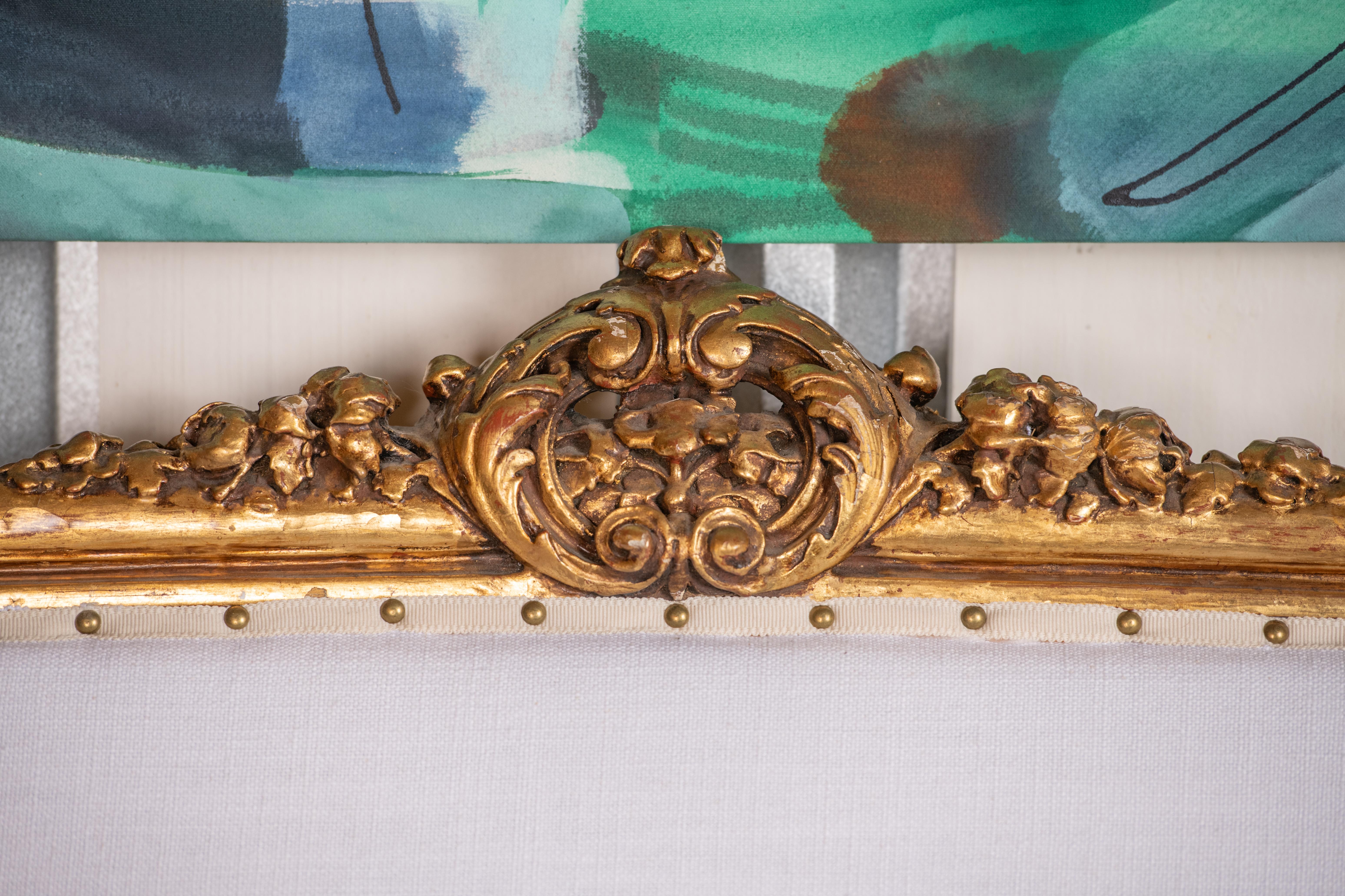 Elegant canapé en bois doré de style Louis XVI avec une nouvelle tapisserie en lin, des rubans et des têtes de clous. Le corps du canapé est décoré de détails floraux en relief, de pieds cannelés et d'un dossier ouvert avec des rails apparents pour