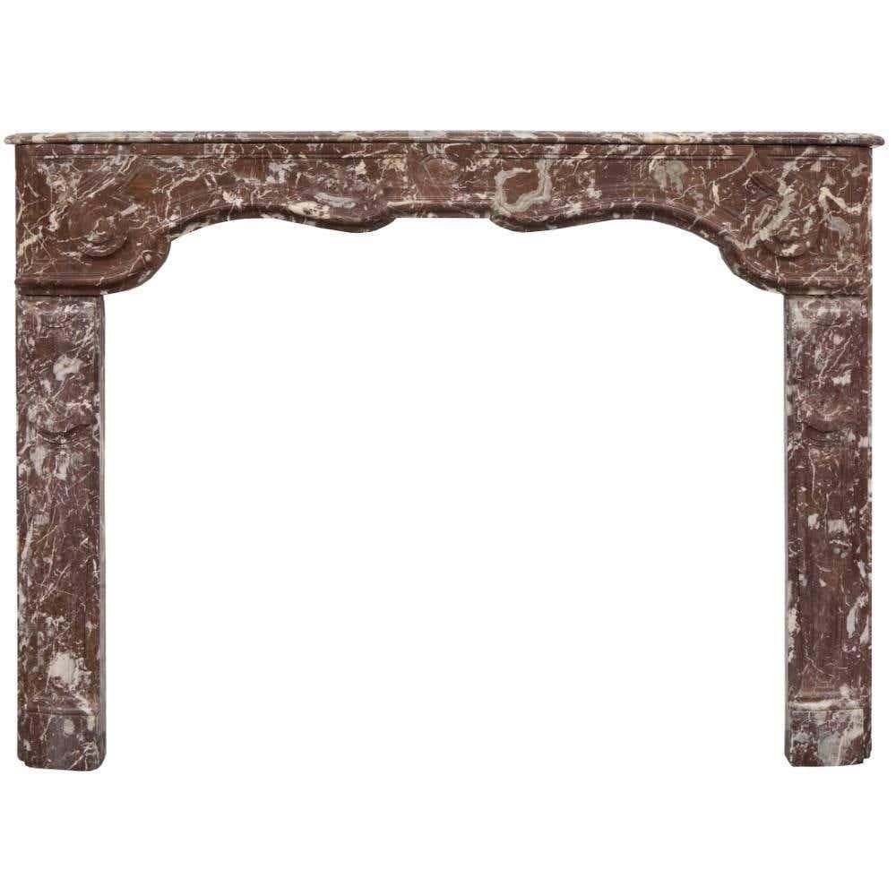 Beautifully understated, hand-carved Louis marble fireplace, late 18th century French rouge marble fireplace. A very rare serpentine shaped frieze with scrolls to each end. Recessed panel moldings carved into both jambs and frieze which sets it off