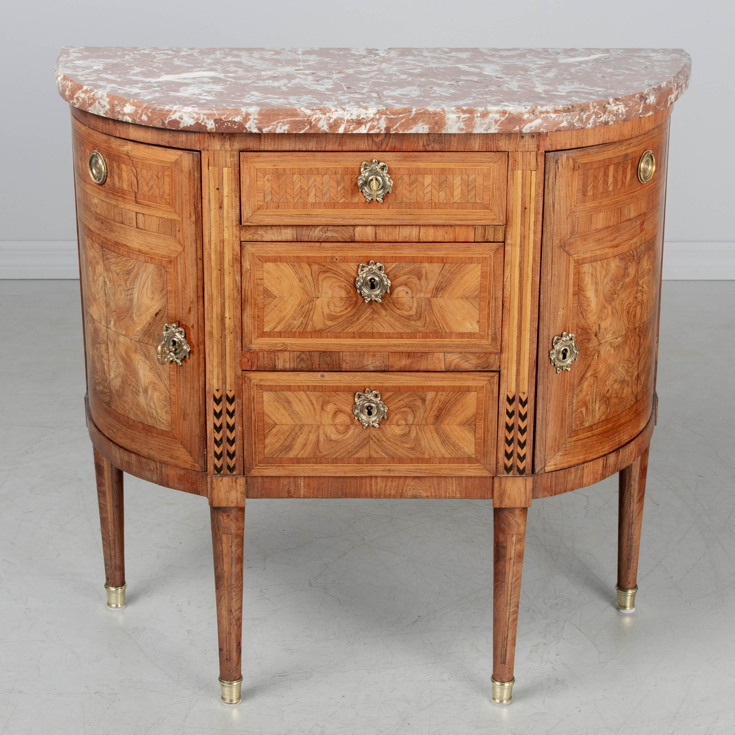 Commodo francese in stile Luigi XVI della fine del XVIII secolo, realizzato in mogano con intarsi di mogano, noce e Wood esotici. Lavorazione artigianale di pregio con impiallacciature abbinate e intarsio a spina di pesce. Tre cassetti a coda di