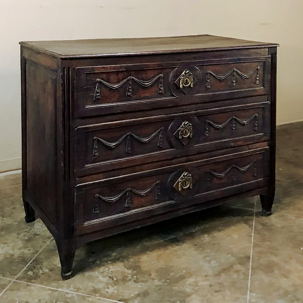 18th Century Louis XVI Period Country French commode was sculpted from solid indigenous old-growth oak, and features neoclassical embellishment hand-carved by a talented artisan across the entire facade. Draped linens and ribbon are the motifs,