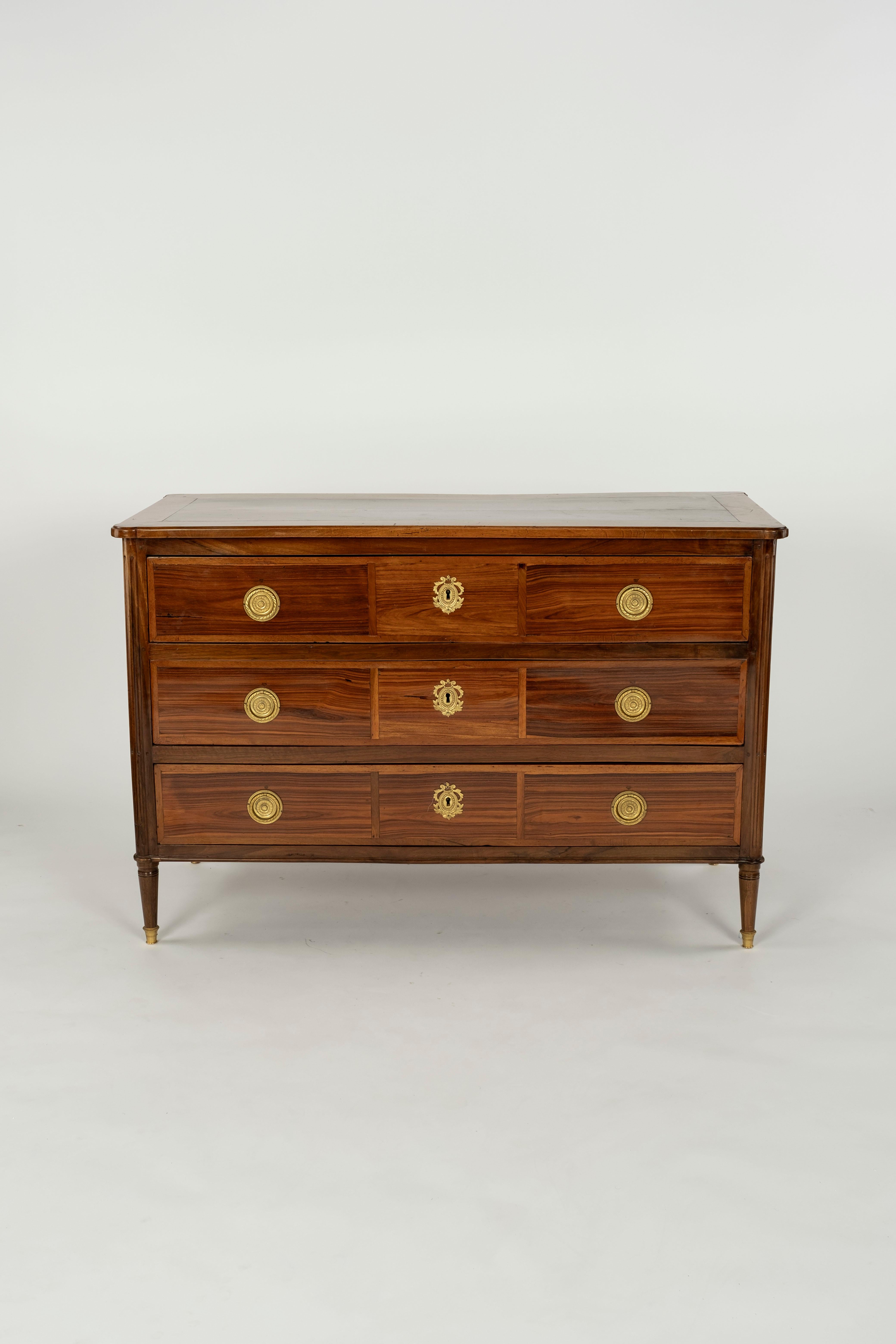 French Louis XVI rosewood commode, attributed to Nicolas Petit (French, 1732-1791, master 1761), 18th c. and later elements, three drawers flanked by fluted corner posts, rising on tapered cylindrical legs, ending in metal-capped feet, later
