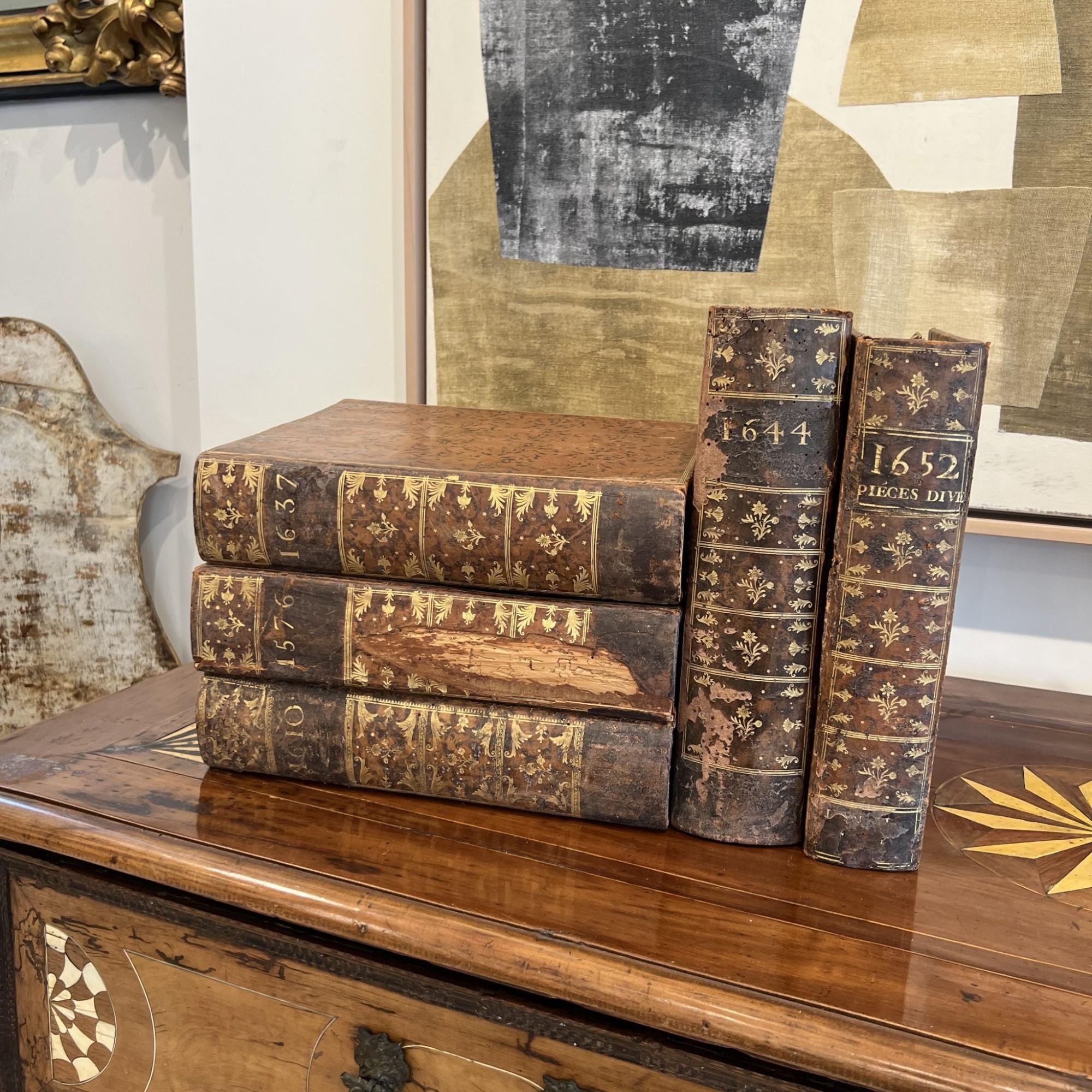 A set of wooden boxes designed to resemble leather-bound books offers a clever and decorative storage solution. Crafted with detailed spines and faux-leather finishes, these boxes blend seamlessly into bookshelves while concealing small items