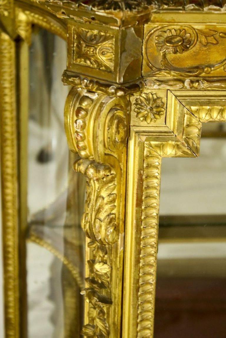 Marvellously carved wood with gilt-over-plaster French vitrine in the style of Louis XVI, circa 1790. The exquisitely carved exterior hand-detailing of acanthus scrolls and vitruvian waves of floral bouquets are complemented by precisely fluted