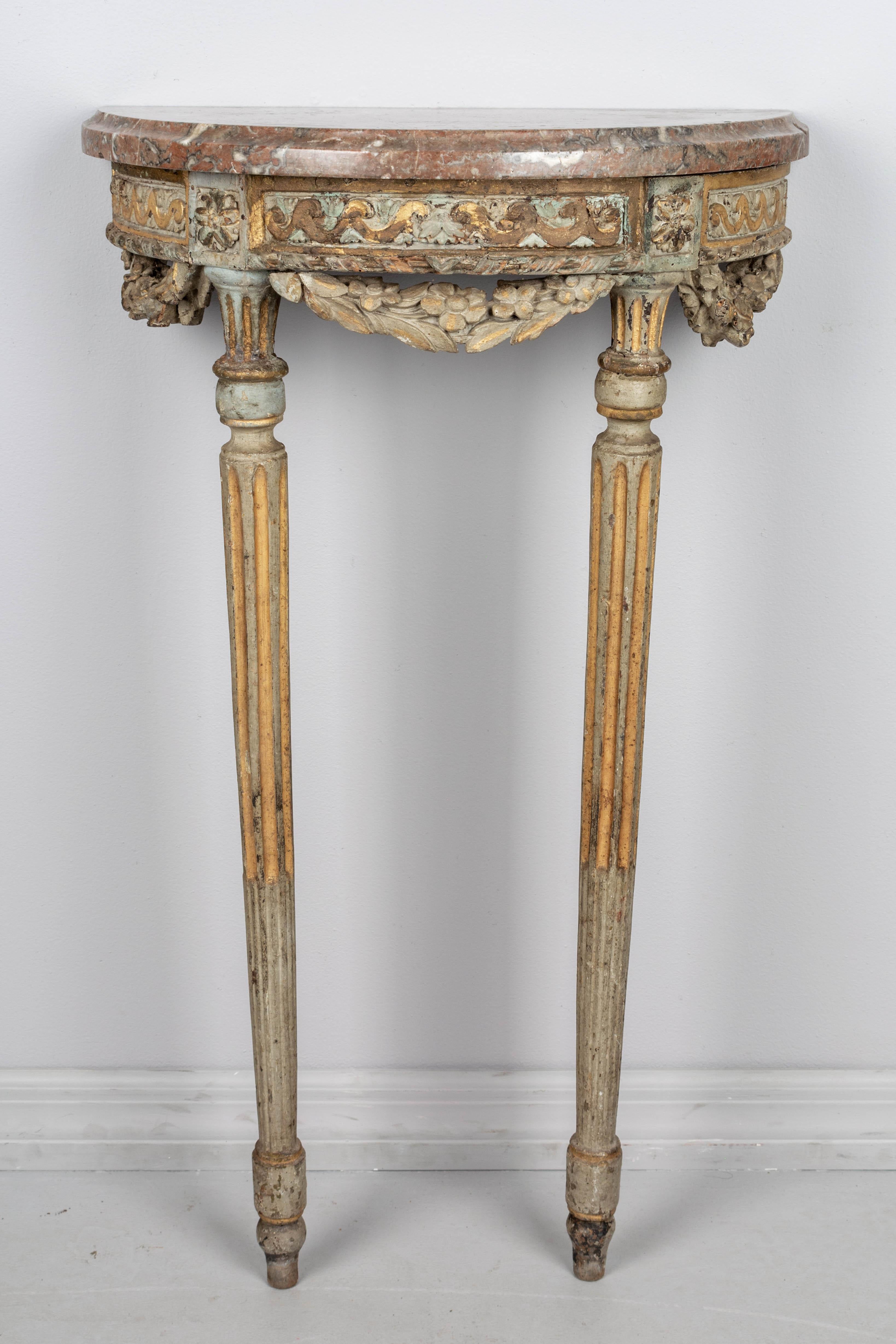 A small late 18th century Louis XVI style French polychrome painted parcel giltwood demilune console table. Beautiful verdigris patina accented with remnants of gilt. Nice sculptural form with three carved floral swags and slim fluted tapered legs.