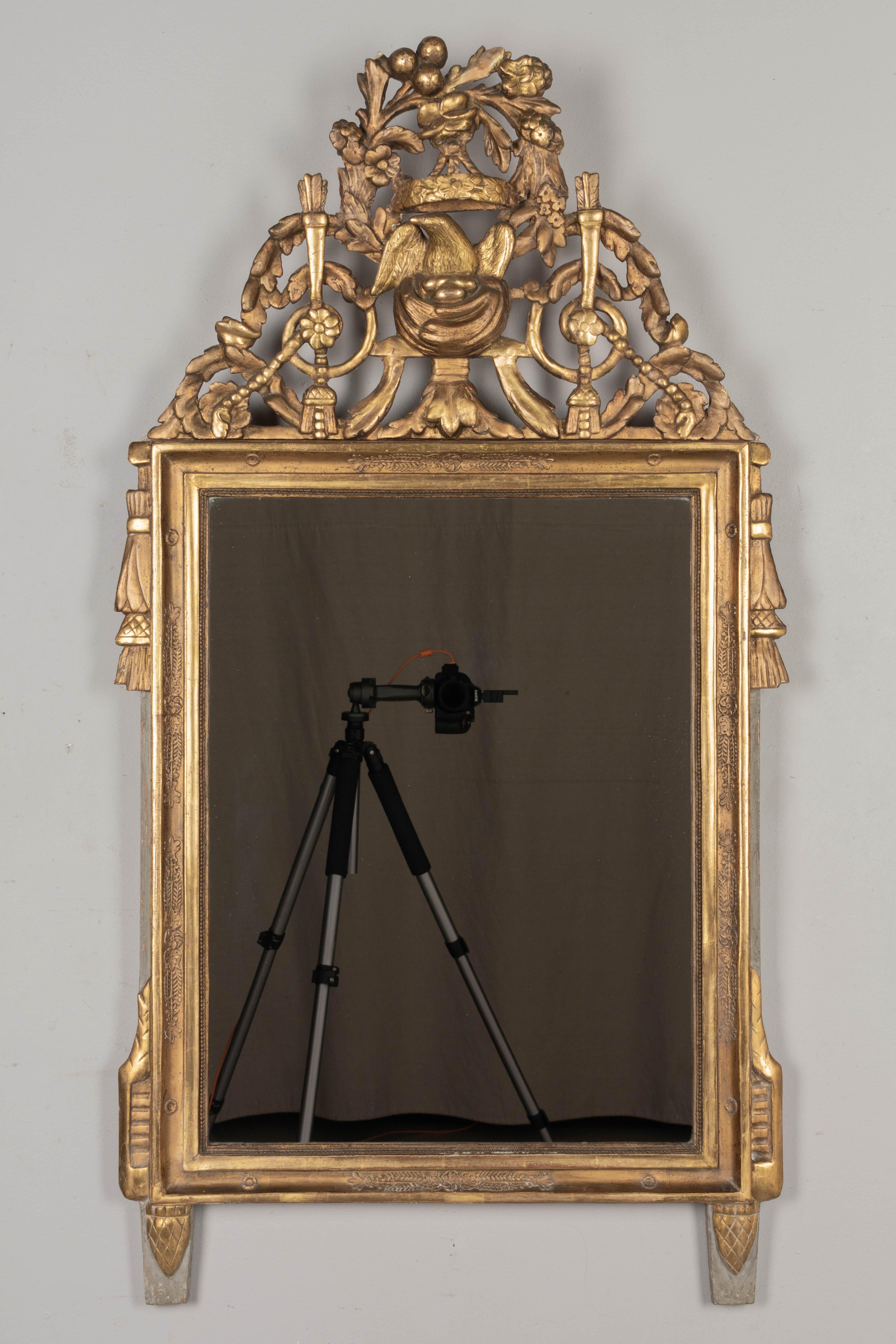 Miroir de style Louis XVI de la fin du XVIIIe siècle. Cimier sculpté en trois dimensions avec un nid d'oiseau sous une couronne florale entourée de guirlandes. Magnifiquement détaillé. Bord extérieur et pieds peints en vert-de-gris pâle.