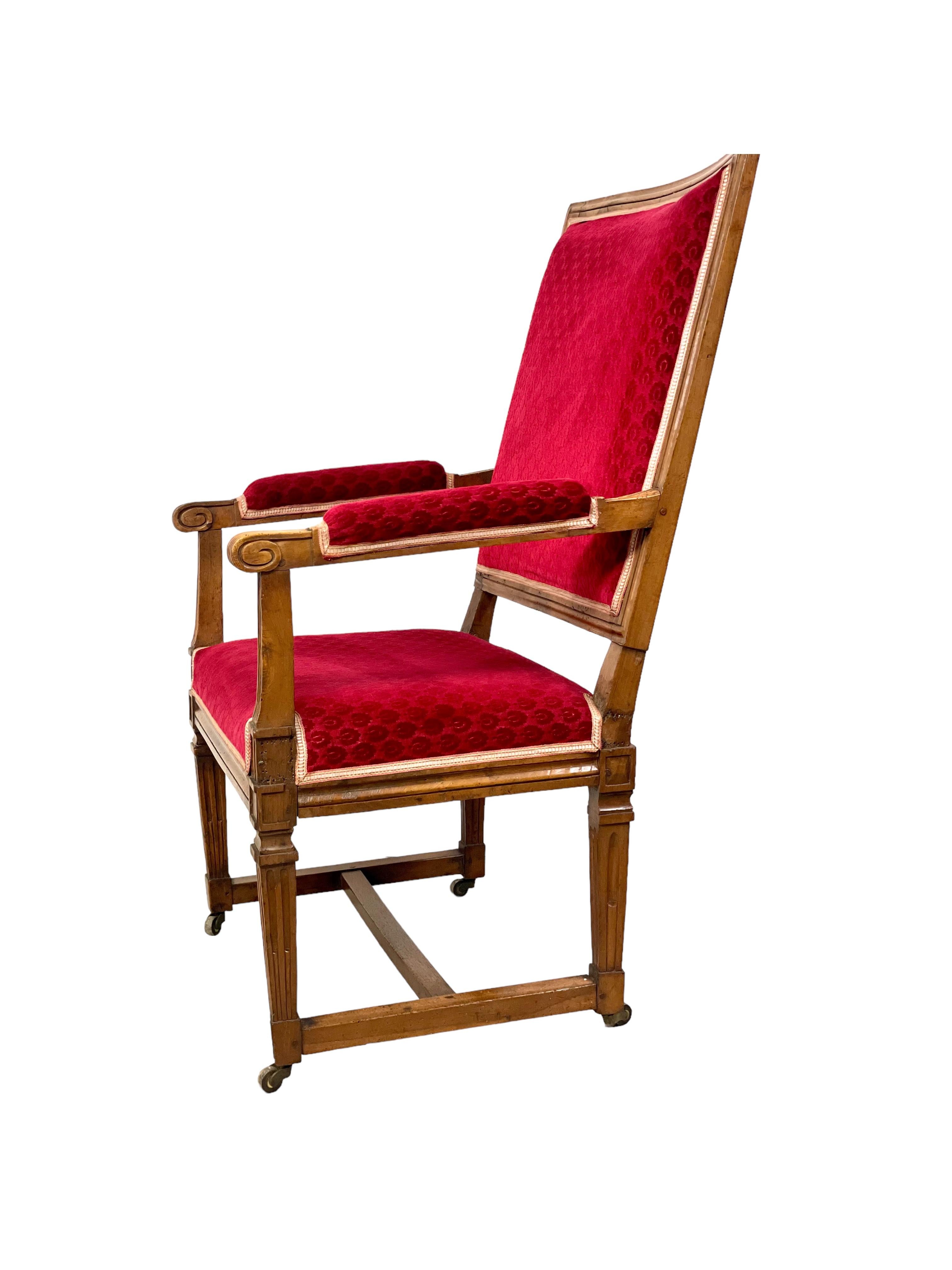 Ce fauteuil français ancien, extrêmement confortable, est un merveilleux exemple du style Louis XVI, avec son dossier carré, rembourré et légèrement incliné, ses pieds cannelés et ses accoudoirs ouverts. Sculpté à la main dans du noyer au XVIIIe