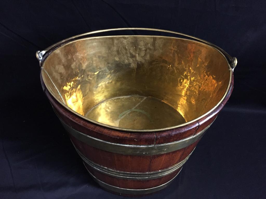 A stunning 18th century mahogany and brass bound wine cooler, the cooler has a brass carrying handle and removable brass liner. The varnished mahogany is bound with two wide brass bands and three central slim brass bands, circa 1720.

    