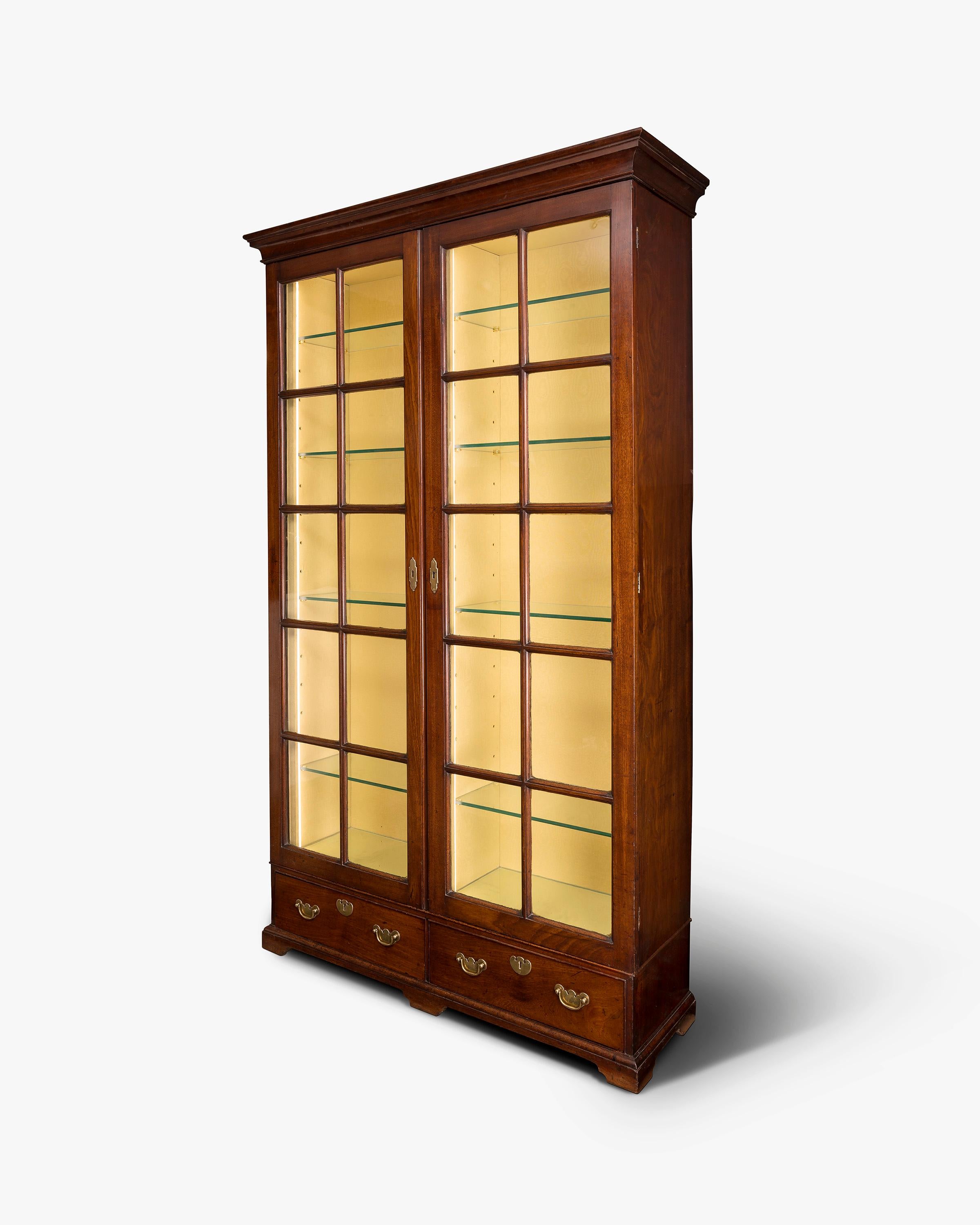 A George II period mahogany library bookcase. Two drawers in the lower section above the bracket feet. Two glazed doors with typically thick George II glazing’s bars.

This piece has been converted for the 21st century by having the interior lined
