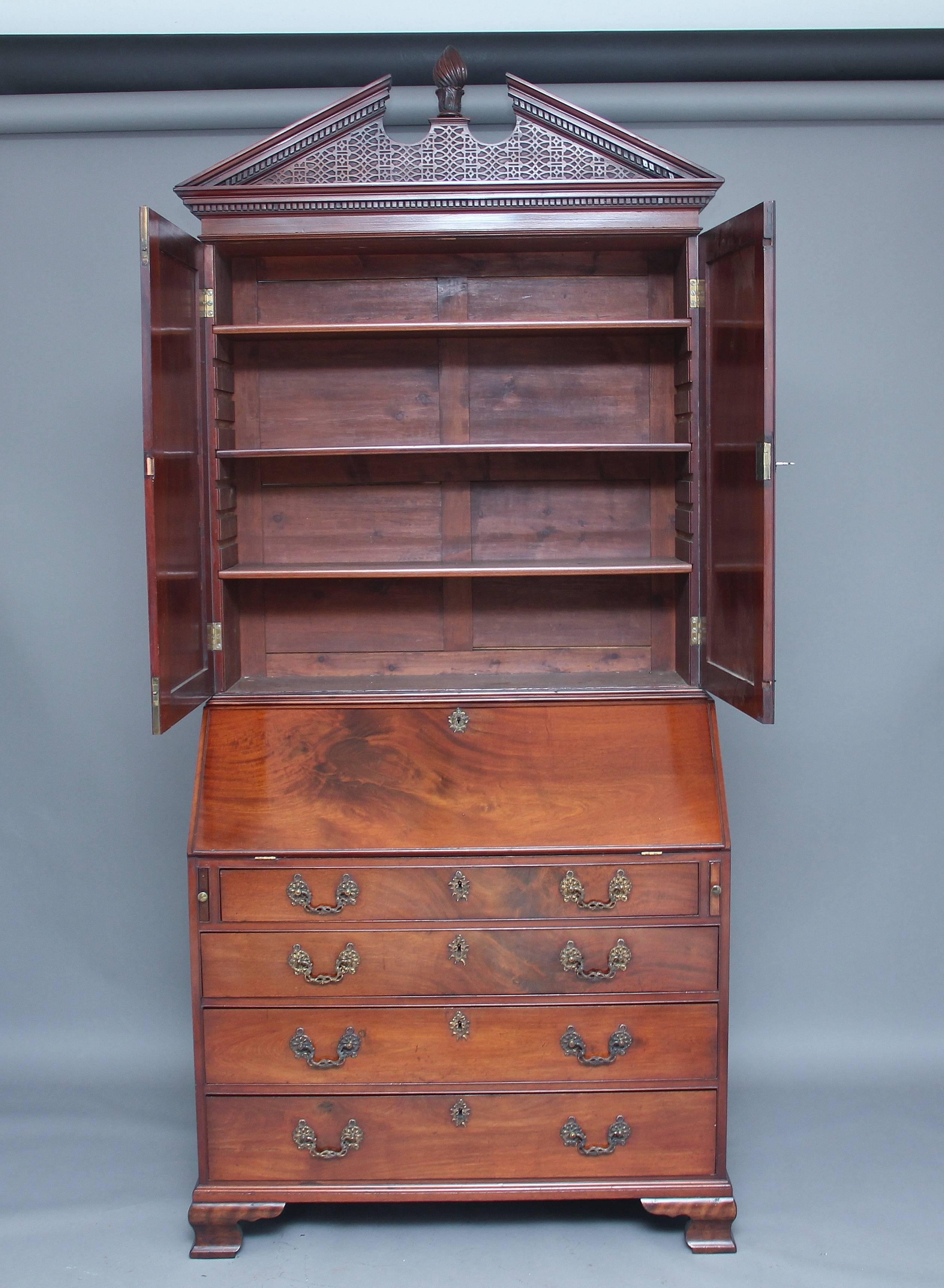 18th century mahogany bureau bookcase, having a broken arch pediment with a carved and turned finial at the centre, decorated with blind fret and dentil moulding, with two fielded panelled doors below opening to reveal three adjustable shelves