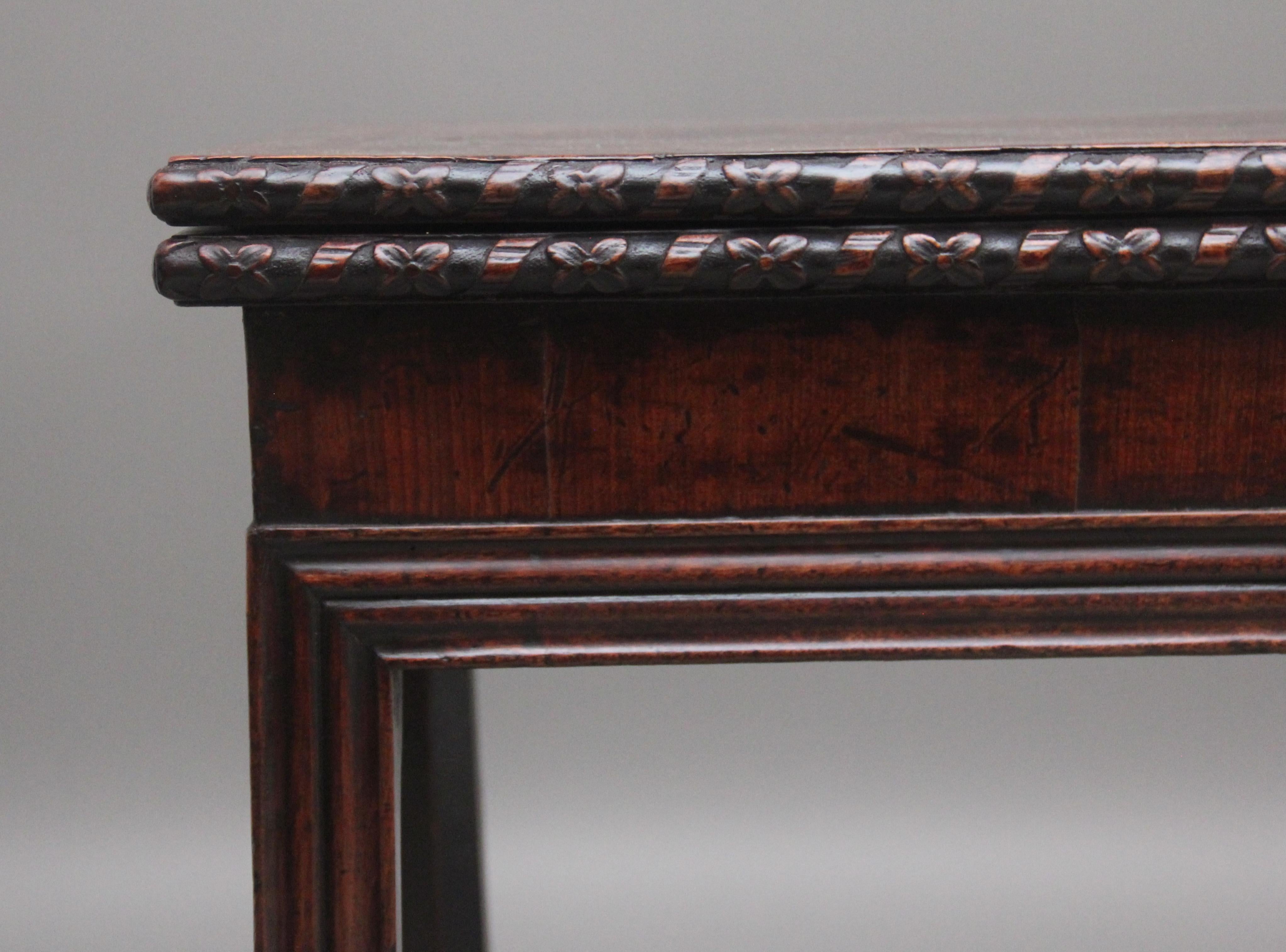 18th Century mahogany card / games table, the rectangular shaped fold over top with a moulded edge with a carved floral decoration, opening to reveal a green baize playing surface, nice figured frieze below and supported on reeded sqaure legs.  The