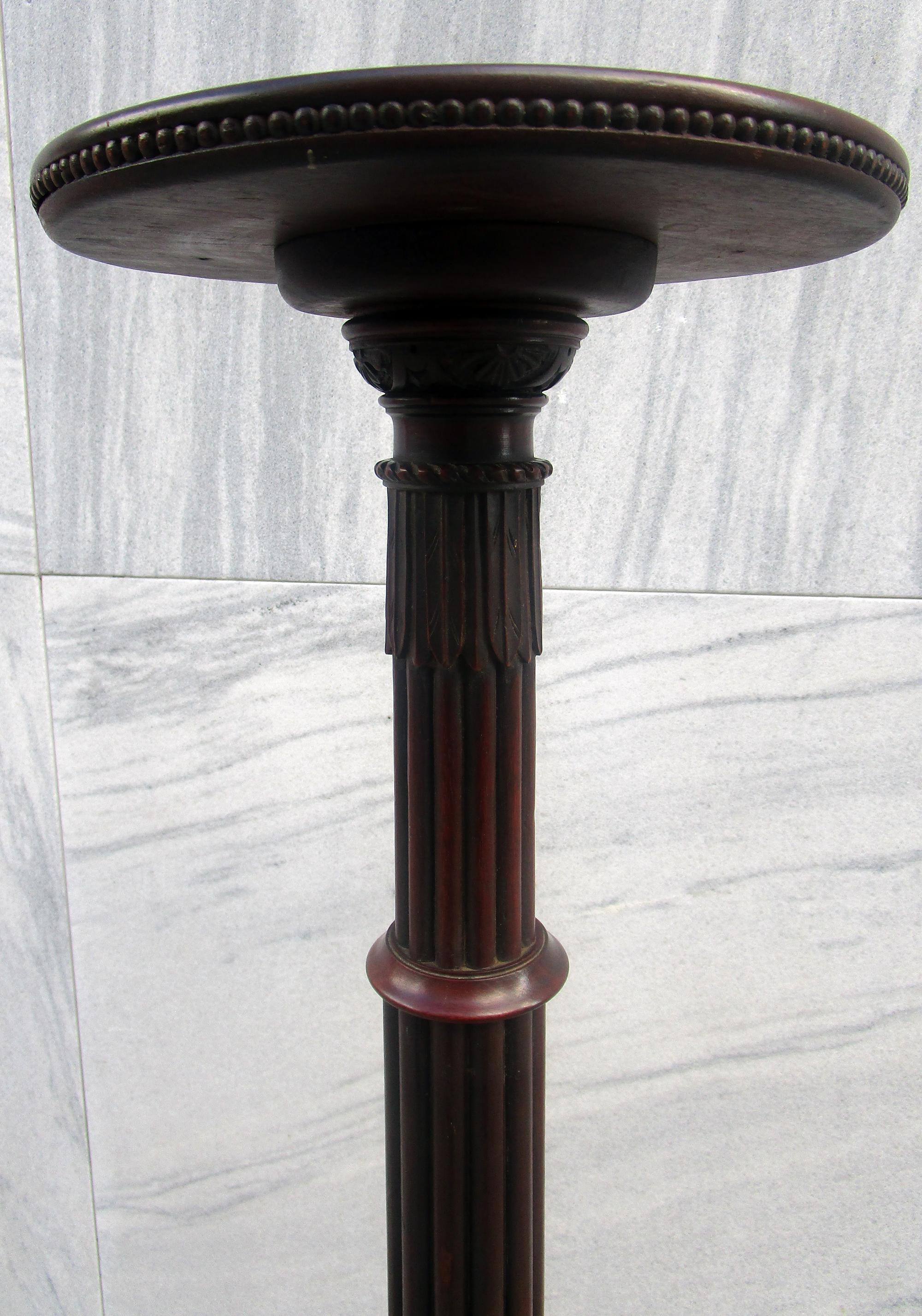 This piece started life in the 1700s as a column to a four tall poster bed. In the 1800s one of the post columns was converted into this plant stand by adding a tripod base and circular top. Features include intricate bell flower, fluted, reeded and