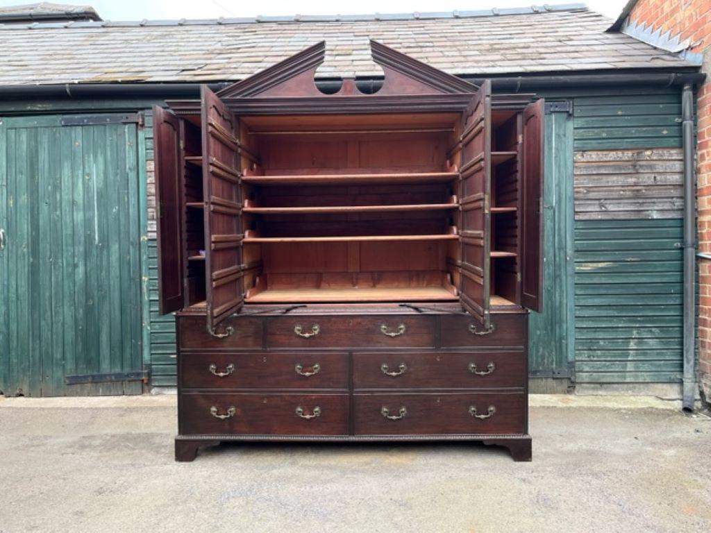 An 18th century Chippendale-period mahogany press cupboard, the base of seven oak-lined drawers with the original brass handles, exquisite carved egg and dart moulding to the lower base, standing on bracket feet.
The architectural breakfront top