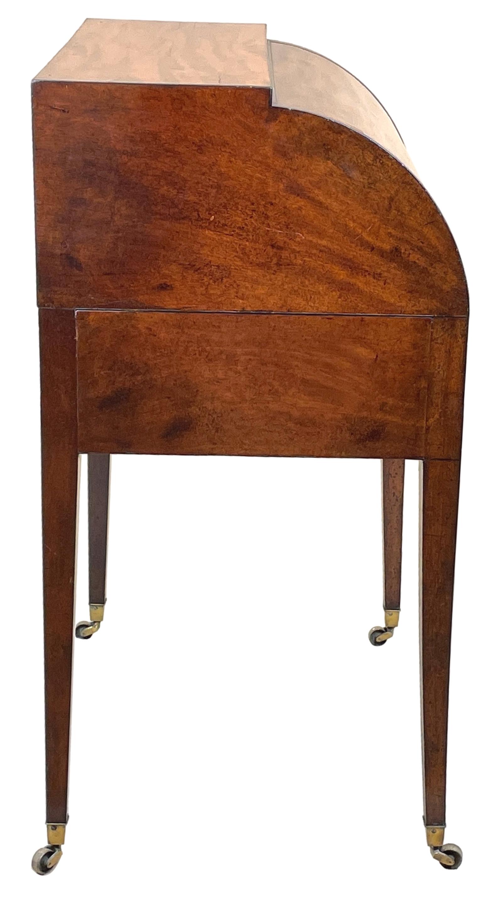 A very good quality late 18th century Georgian mahogany cylinder desk having well figured roll top, enclosing baize sliding writing surface with ratcheted slope and interior drawers, over two short and one long frieze drawers retaining elegant