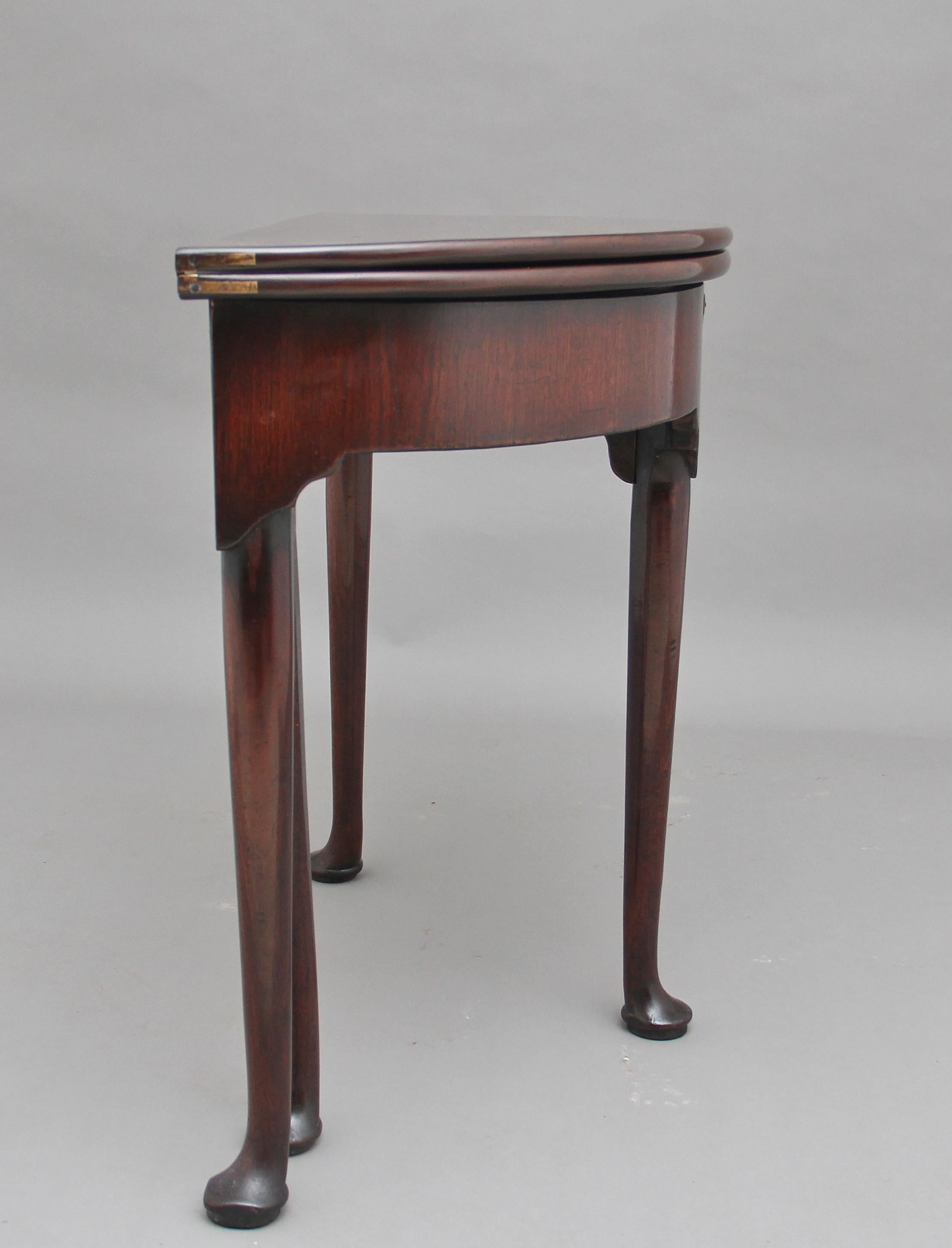 18th century mahogany demilune tea table, the double fold over top encloses an spacious compartment, standing on four slender turned legs terminating on pad feet, the table has a lovely rich warm color, circa 1780.