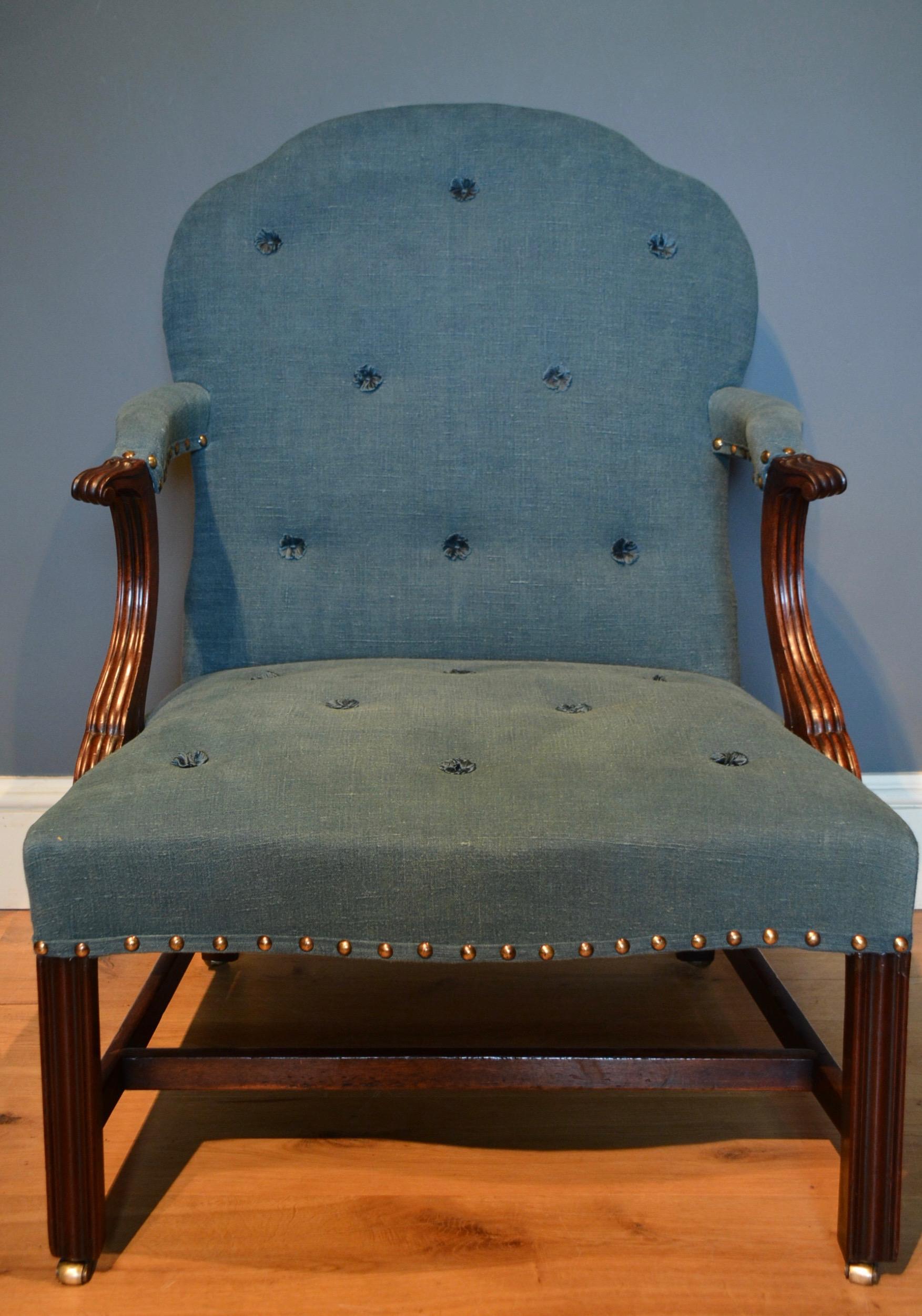 A George III mahogany Gainsborough chair, the shaped upholstered back and seat with reeded and paneled scroll arms standing on molded front legs.