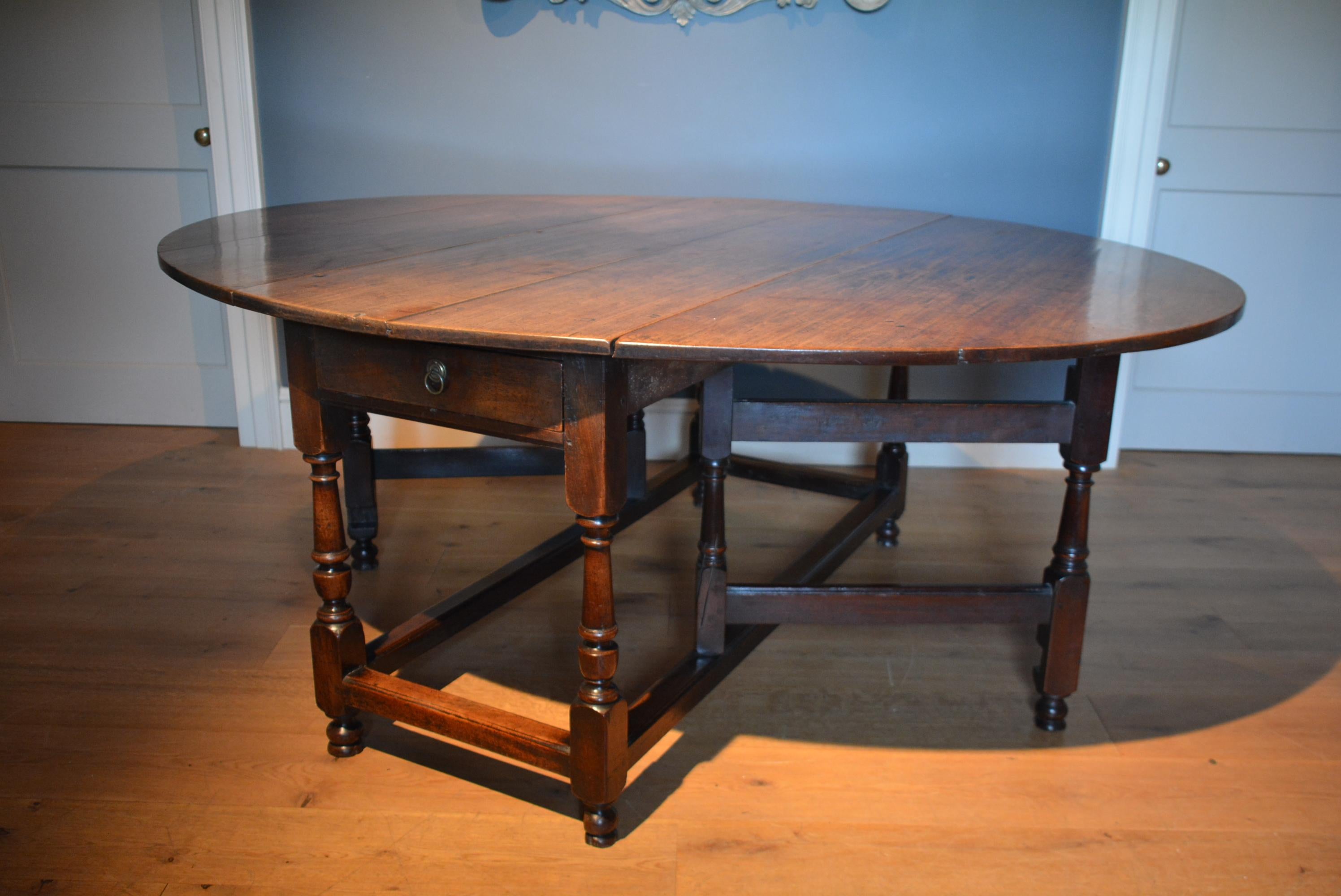 An unusually large early 18th century mahogany gateleg table of exceptional color and patination, the end friezes each containing a drawer above the turned and stretchered base standing high on it's original feet.

 