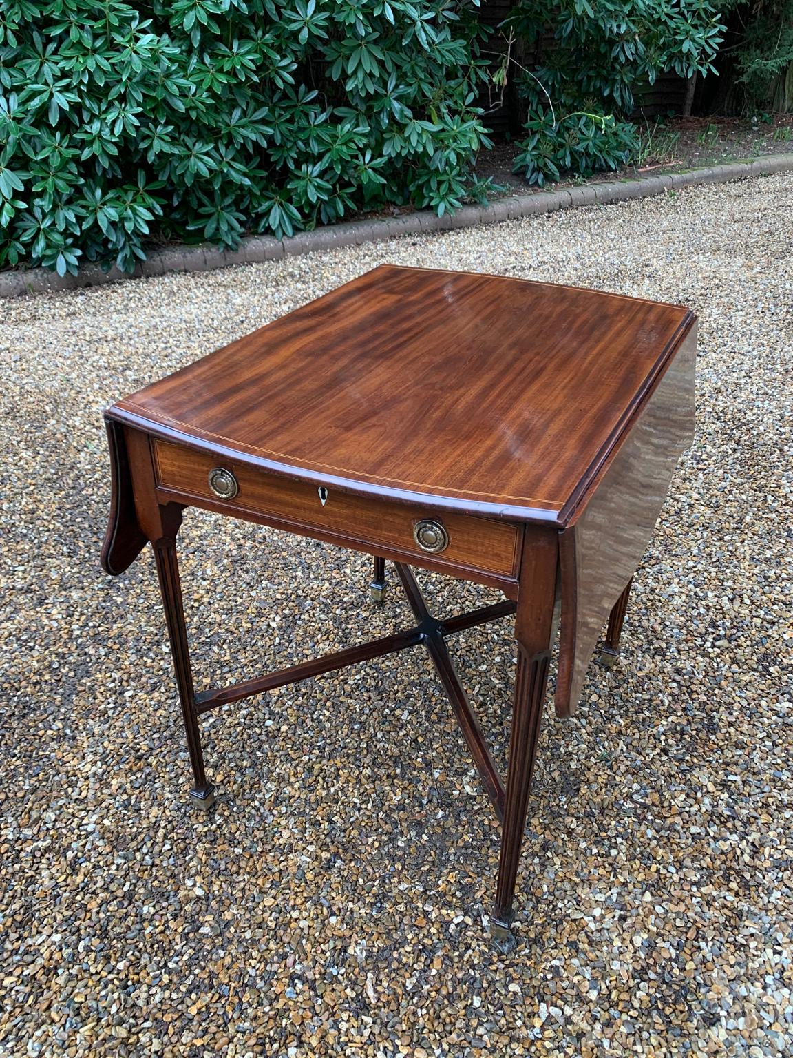 A very good quality 18th century mahogany pembroke butterfly / serpentine table, with an inlaid edge on top, a single drawer and standing on elegant square tapered legs supports united by ‘X’ stretcher with brass castors to base.
