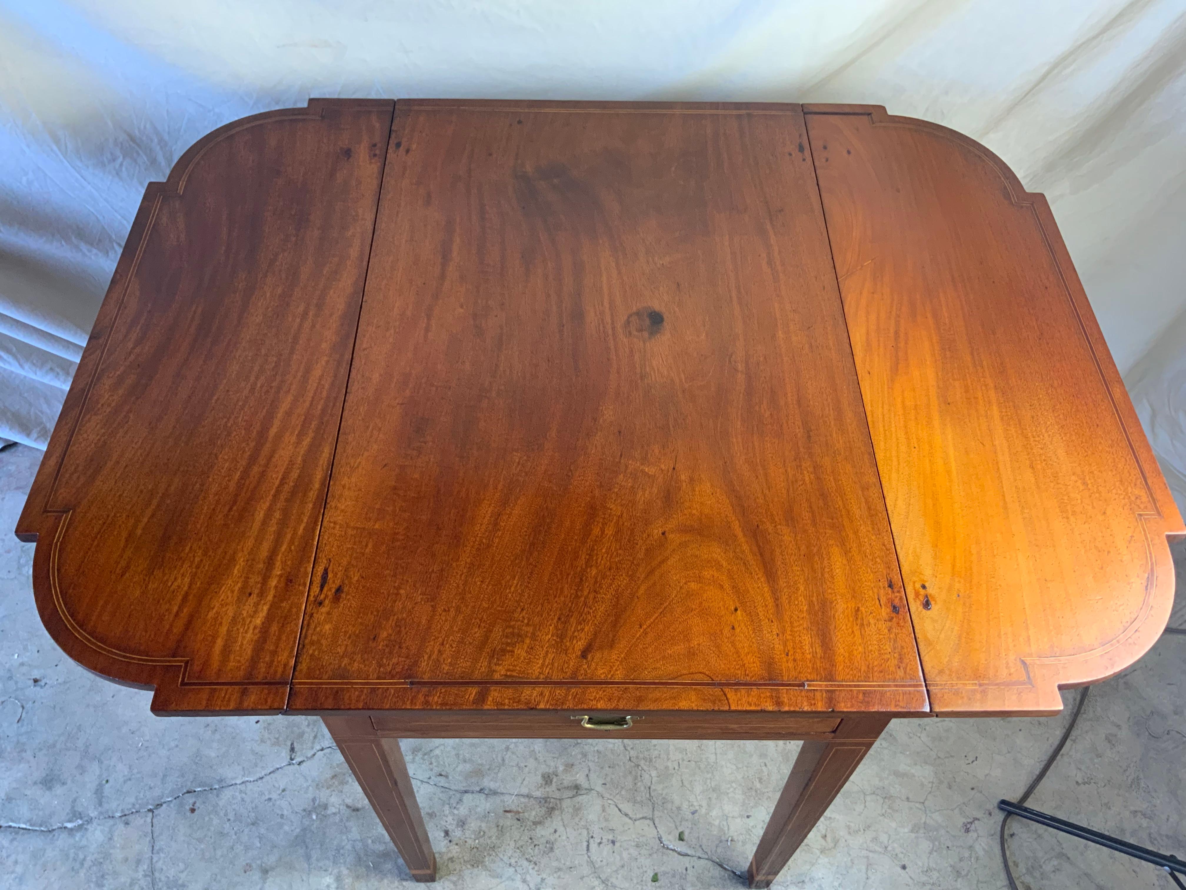 A very nice Mahogany inlay Pembroke table with cut corners on the drop leaves. Great color and patina on the old surface. Pulls on the active and fixed drawer face are a later replacement. All hinges are original to the piece. Wear and surface